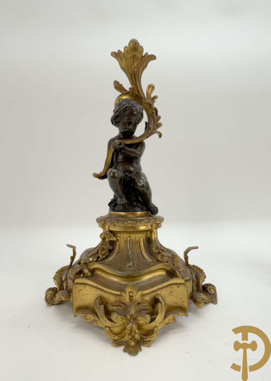 Driedelige bronzen garnituur bestaande uit middenstuk met bronzen vuurvergulde klok, Daubrée gemerkt à Nancy, bovenaan bekroond met Cleopatra met drinkbeker - getekend van Cumberworth sculpteur - geflankeerd door paar cupido