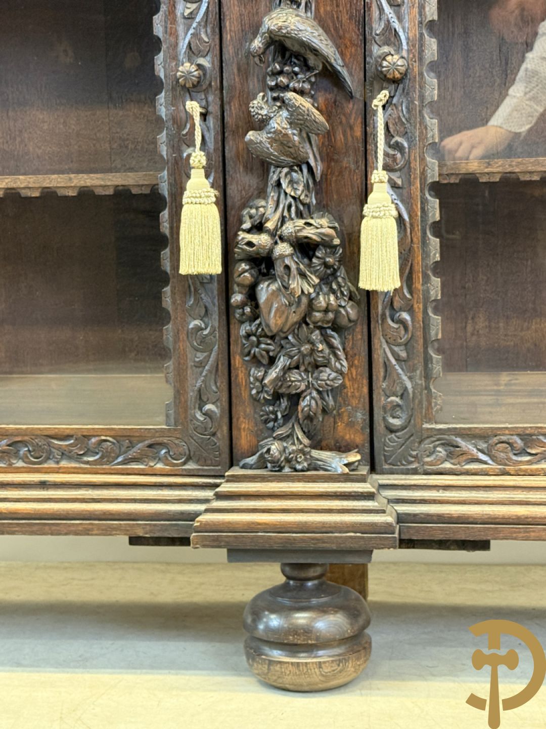 Tweedeursvitrine met Neo Renaissance sculptuur, bovenaan mlet cupidohoofden, bloemen en accanthusranken