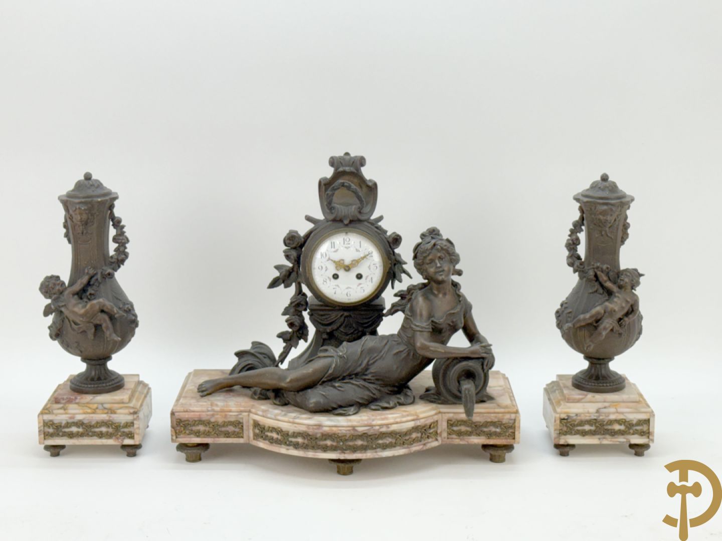 Driedelige kunstbronzen garnituur bestaande uit klok met liggende dame met amfoor op marmeren basis, geflankeerd door paar cassolettes met cupido