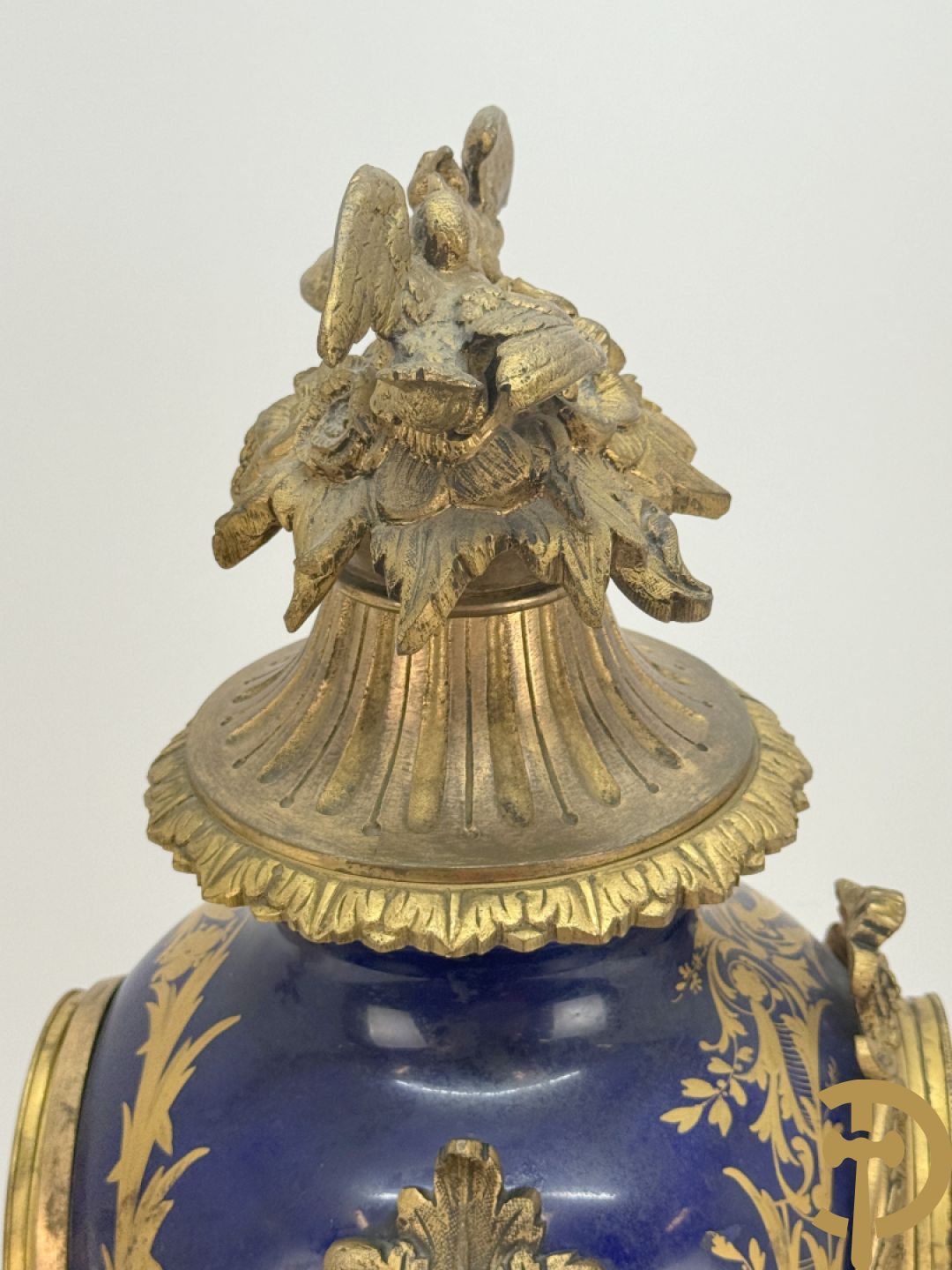 Driedelige vergulde bronzen garnituur bestaande uit pendule met blauw porseleinen coupe geflankeerd door 2 cupido