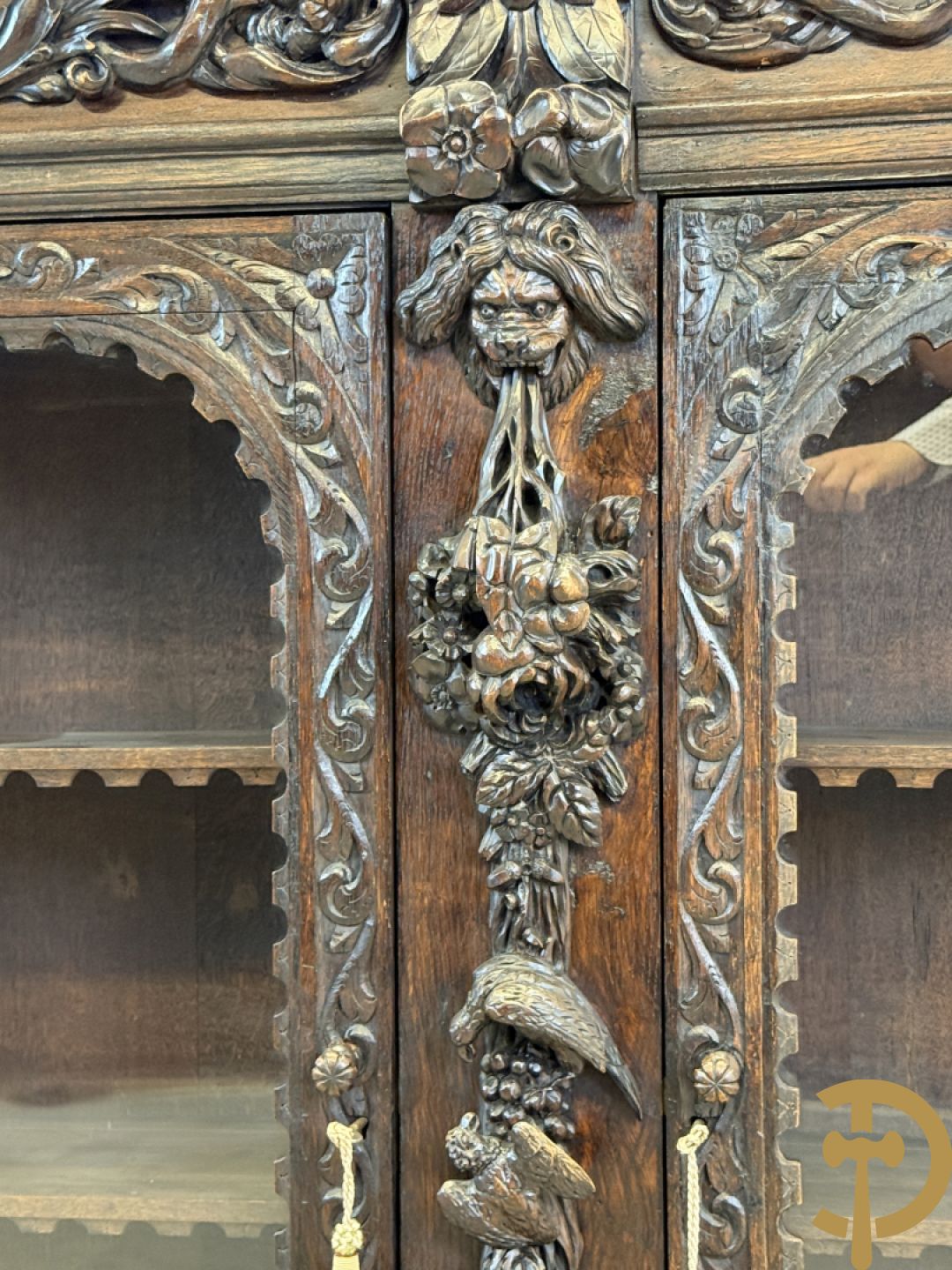 Tweedeursvitrine met Neo Renaissance sculptuur, bovenaan mlet cupidohoofden, bloemen en accanthusranken