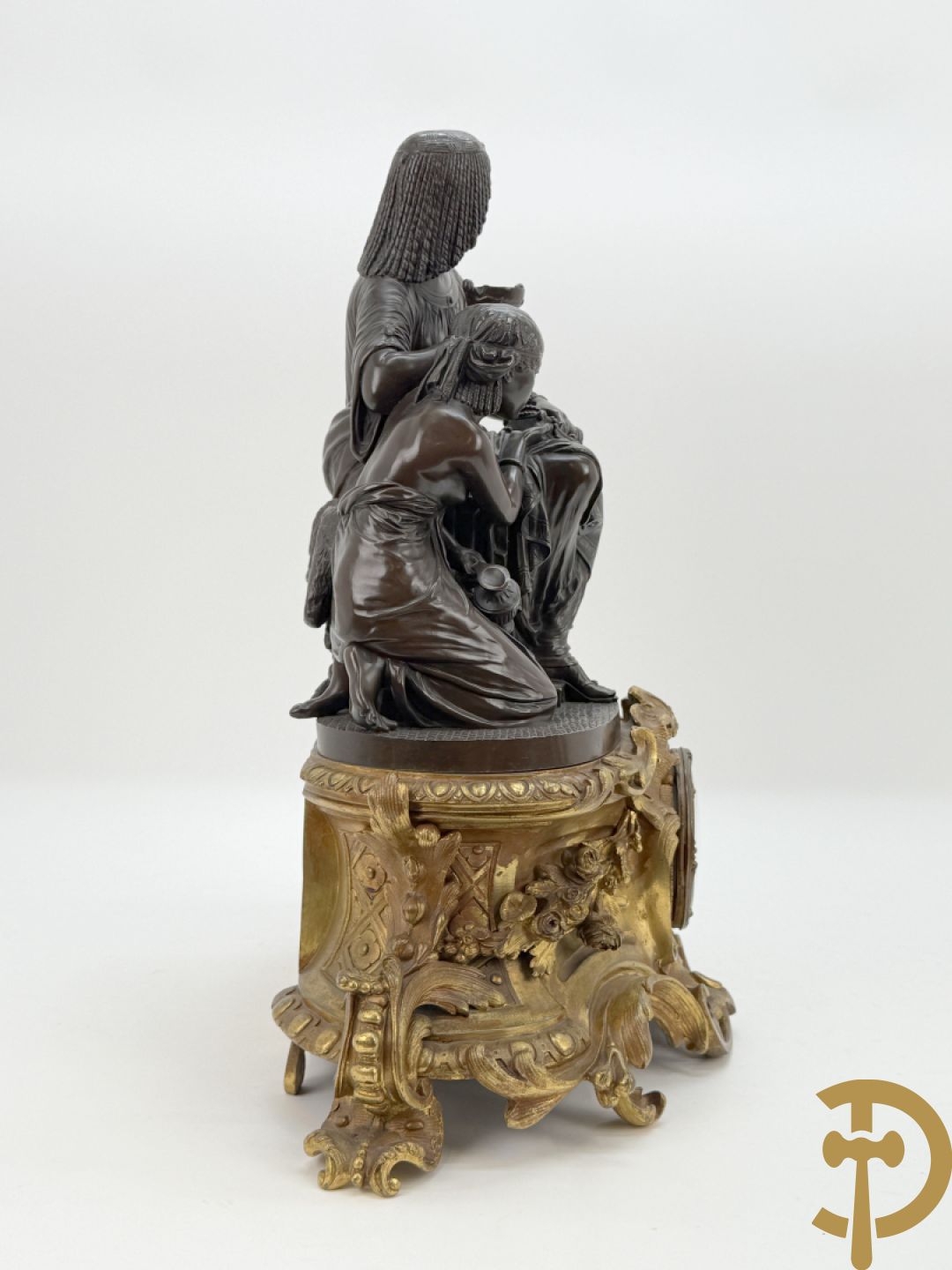 Driedelige bronzen garnituur bestaande uit middenstuk met bronzen vuurvergulde klok, Daubrée gemerkt à Nancy, bovenaan bekroond met Cleopatra met drinkbeker - getekend van Cumberworth sculpteur - geflankeerd door paar cupido