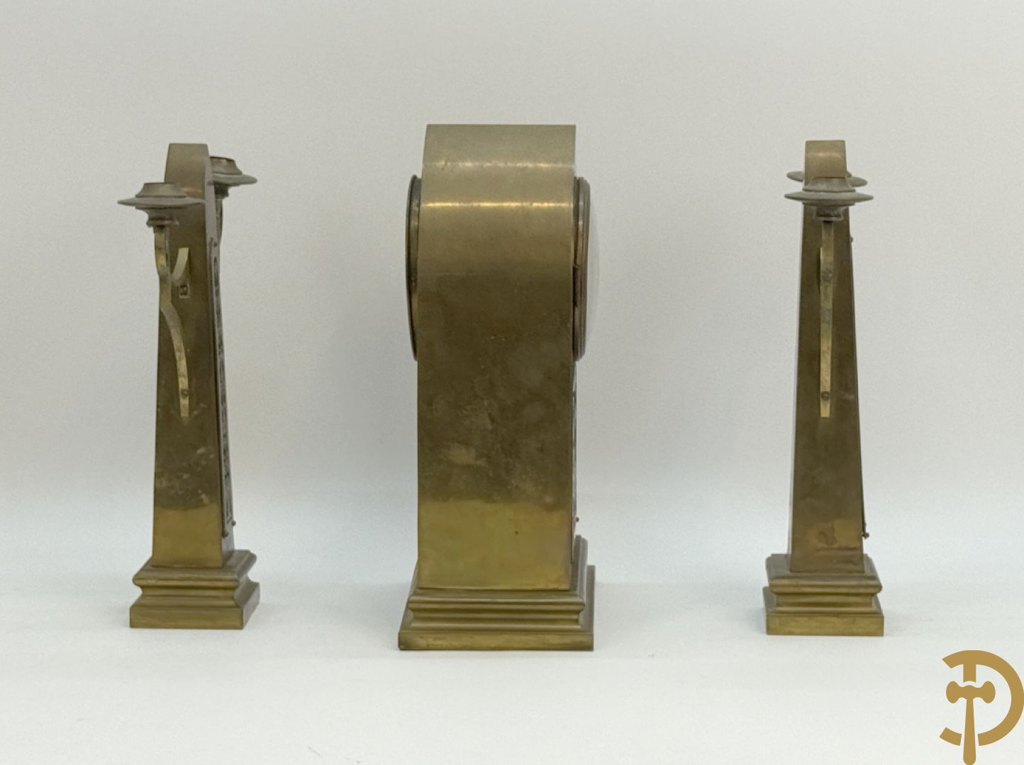Driedelige koperen Art Nouveau garnituur bestaande uit kapelvormige pendule geflankeerd door paar kandelaars