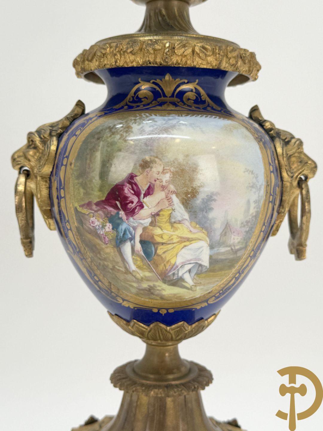 Driedelige vergulde bronzen garnituur bestaande uit pendule met blauw porseleinen coupe geflankeerd door 2 cupido