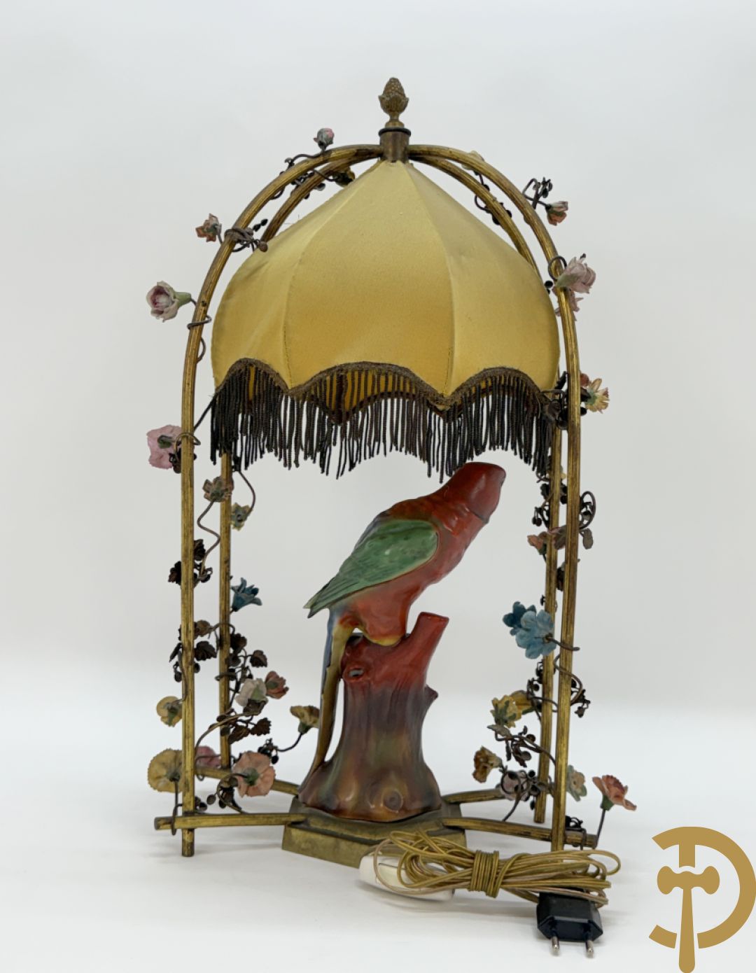 Handgekleurde porseleinen papegaai onder koperen boog met bloemen bezet, als lampadaire