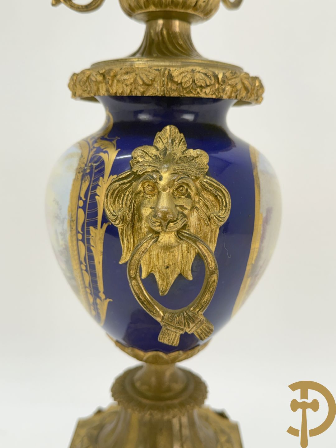 Driedelige vergulde bronzen garnituur bestaande uit pendule met blauw porseleinen coupe geflankeerd door 2 cupido