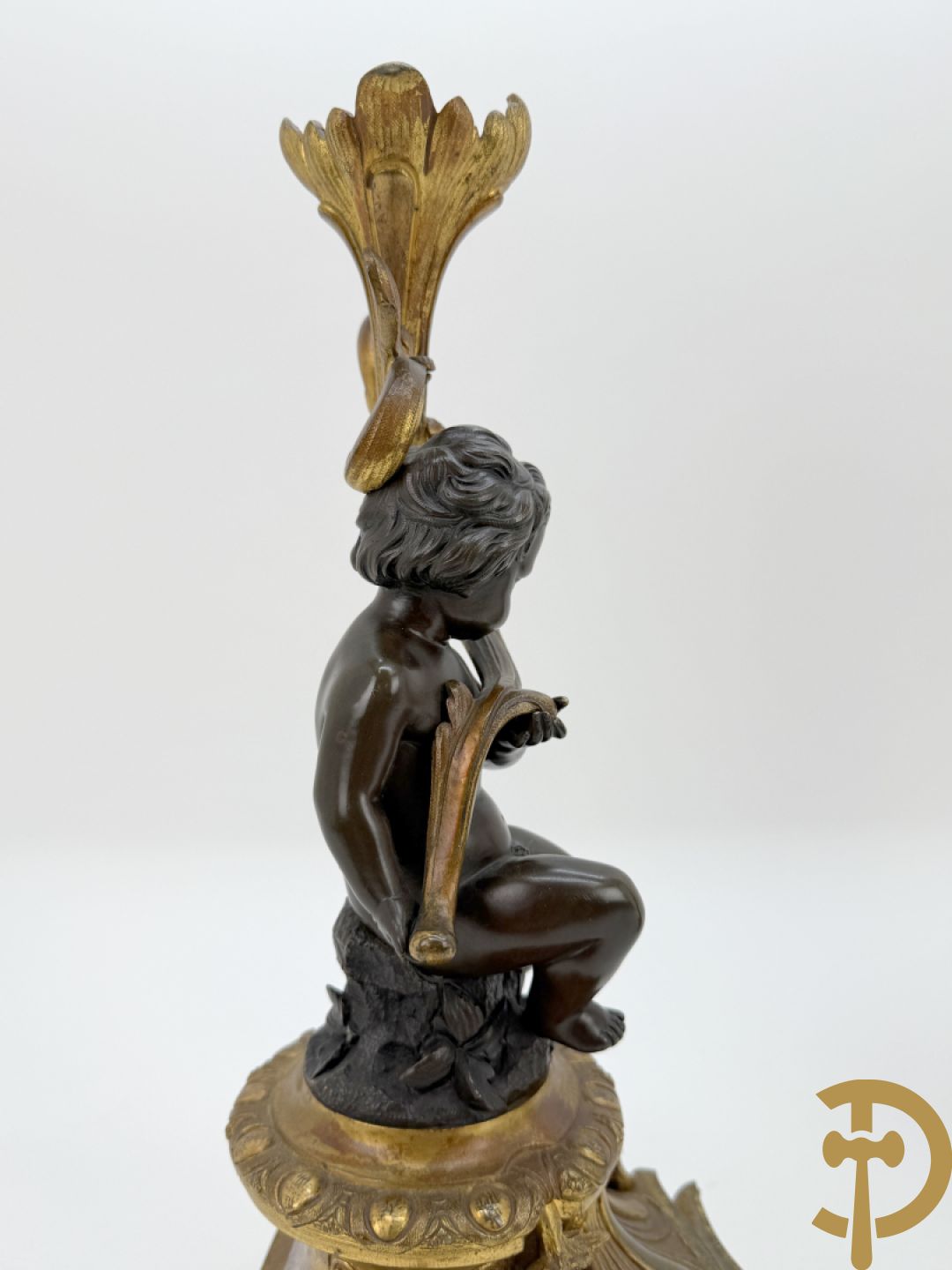 Driedelige bronzen garnituur bestaande uit middenstuk met bronzen vuurvergulde klok, Daubrée gemerkt à Nancy, bovenaan bekroond met Cleopatra met drinkbeker - getekend van Cumberworth sculpteur - geflankeerd door paar cupido