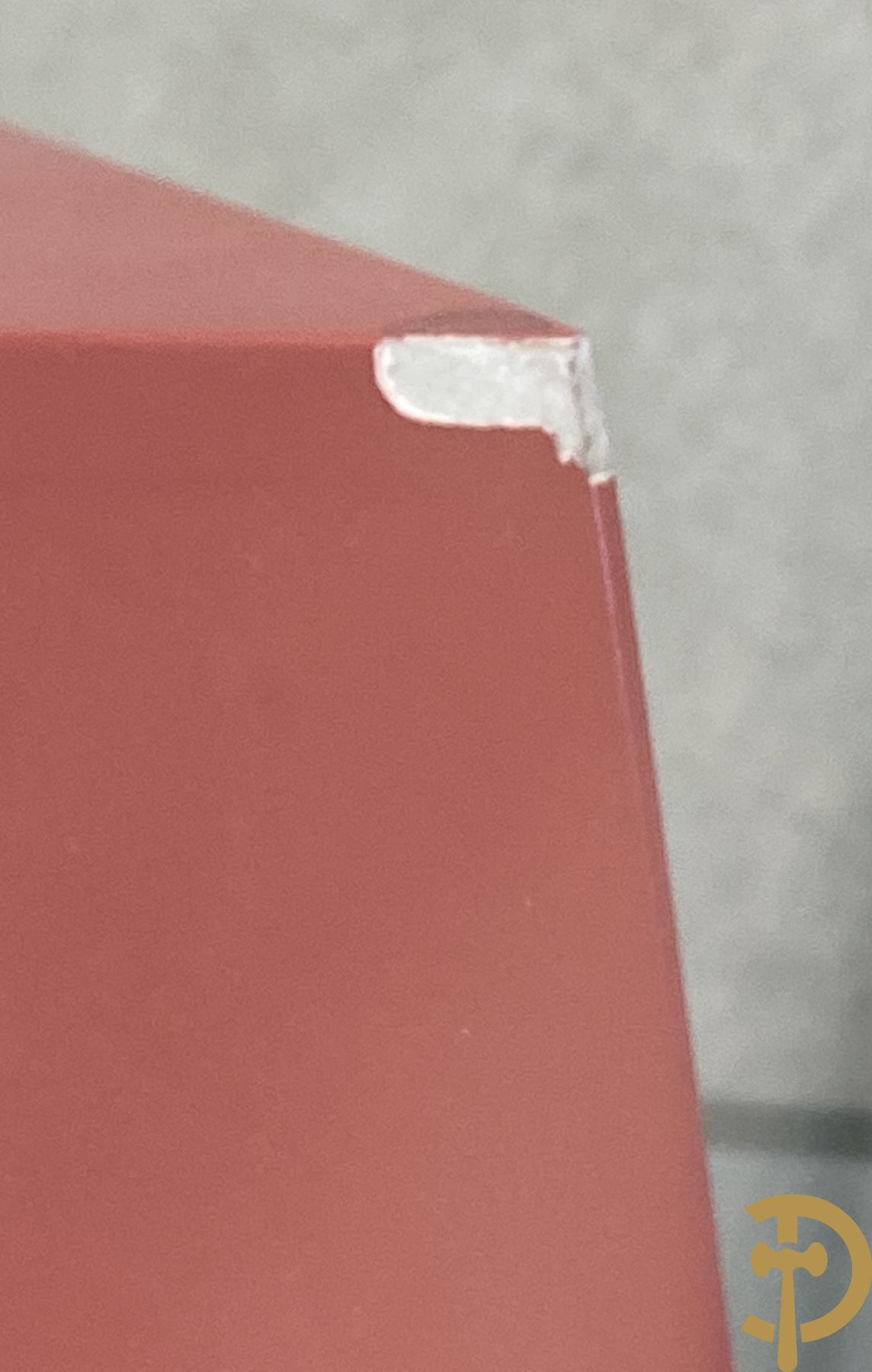 Design salontafel met glazen gepolijst blad op rood gelakte driehoekig prisma sokkel