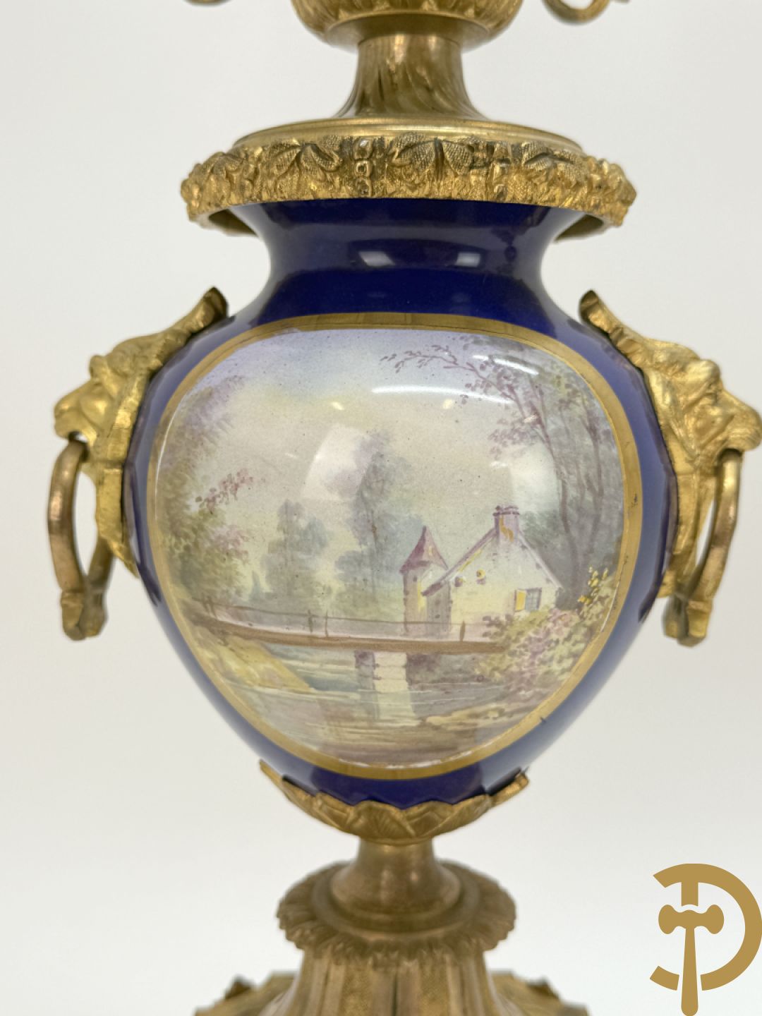Driedelige vergulde bronzen garnituur bestaande uit pendule met blauw porseleinen coupe geflankeerd door 2 cupido
