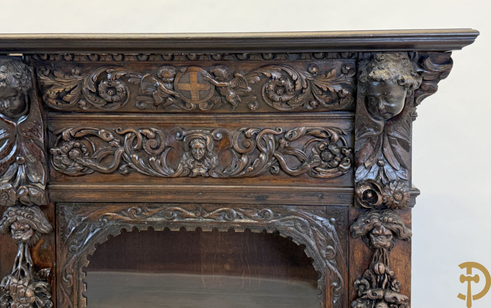 Tweedeursvitrine met Neo Renaissance sculptuur, bovenaan mlet cupidohoofden, bloemen en accanthusranken