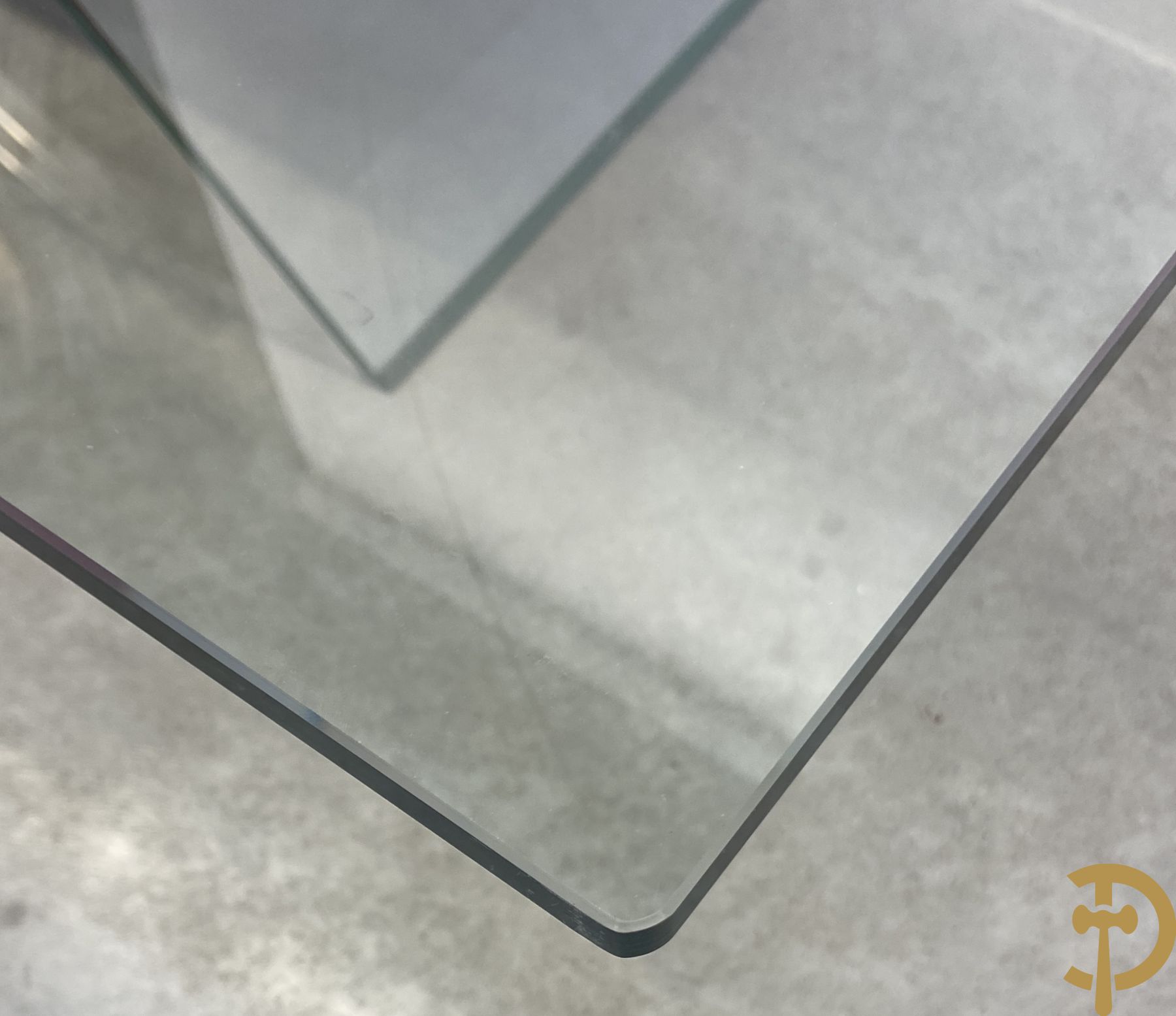 Design salontafel met glazen gepolijst blad op rood gelakte driehoekig prisma sokkel