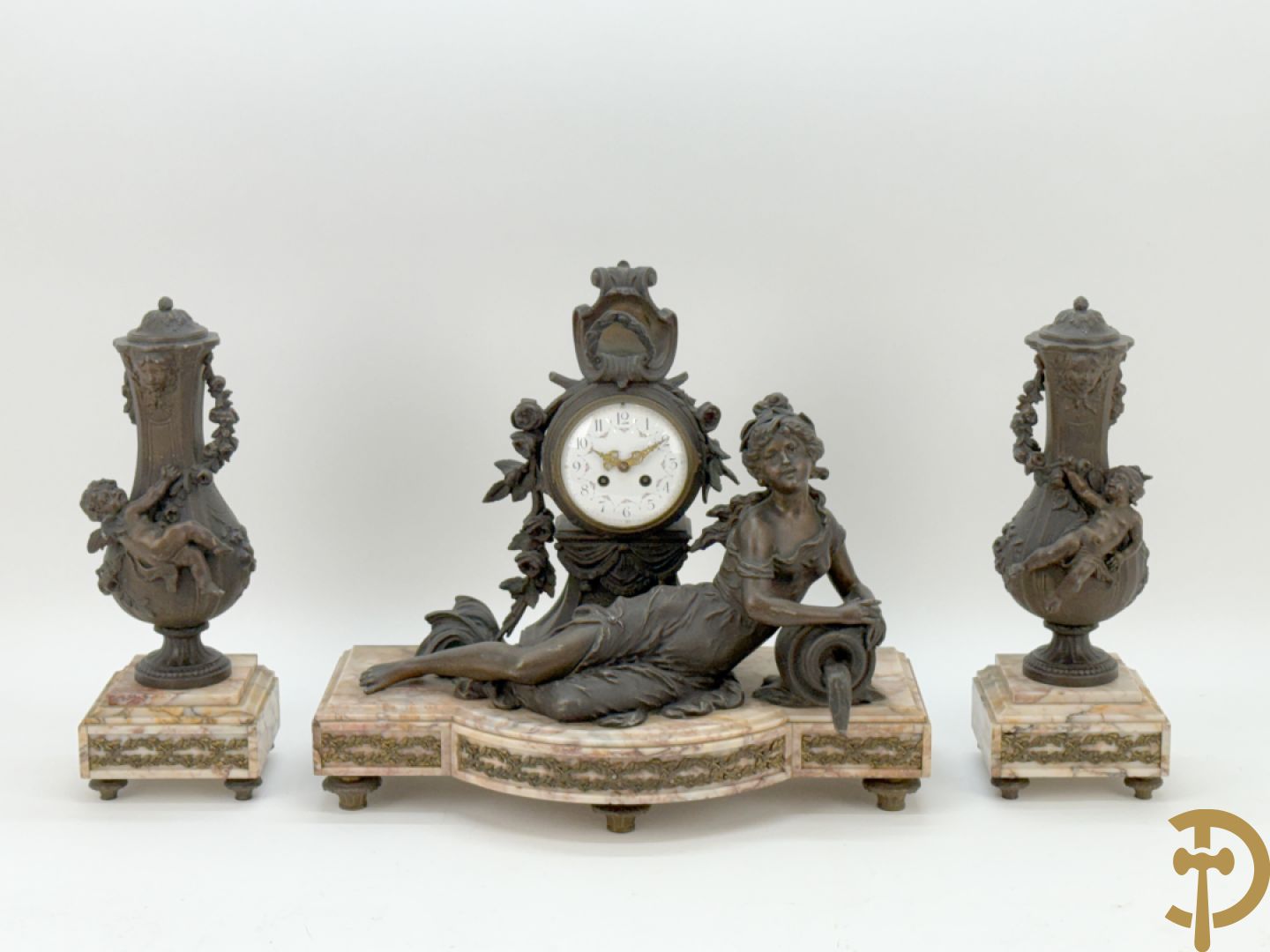 Driedelige kunstbronzen garnituur bestaande uit klok met liggende dame met amfoor op marmeren basis, geflankeerd door paar cassolettes met cupido