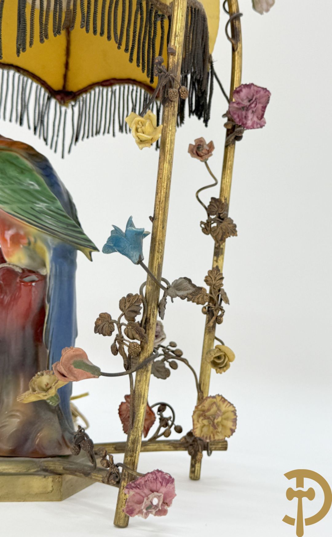 Handgekleurde porseleinen papegaai onder koperen boog met bloemen bezet, als lampadaire