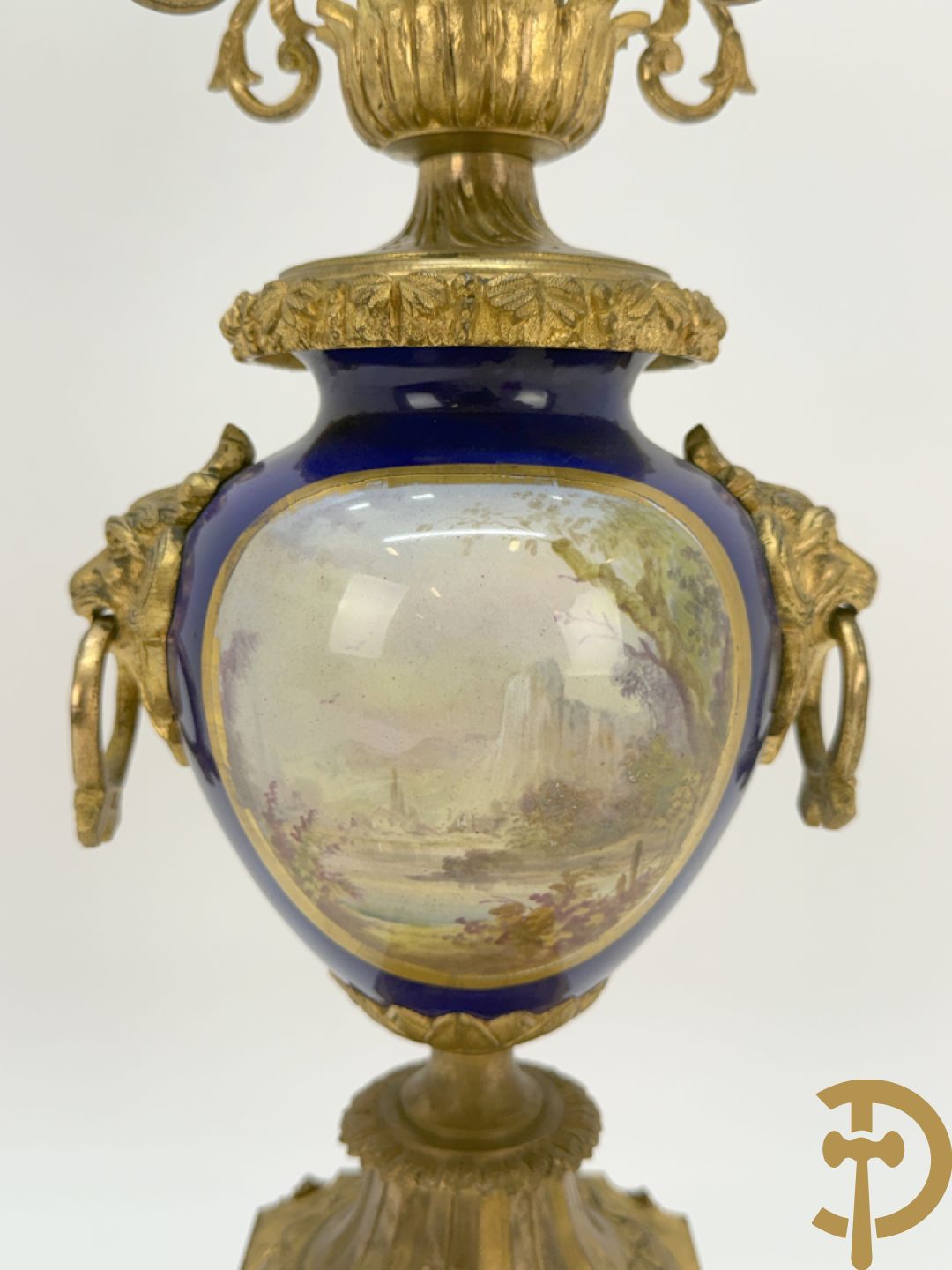 Driedelige vergulde bronzen garnituur bestaande uit pendule met blauw porseleinen coupe geflankeerd door 2 cupido