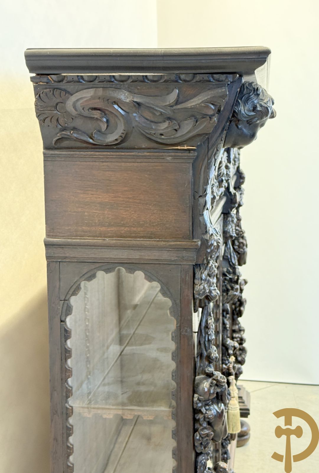 Tweedeursvitrine met Neo Renaissance sculptuur, bovenaan mlet cupidohoofden, bloemen en accanthusranken