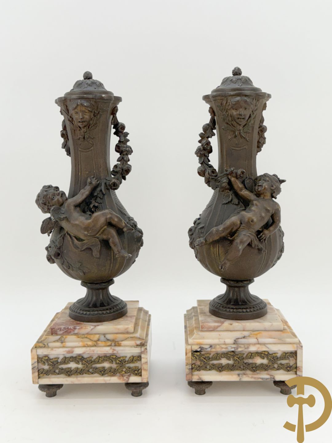 Driedelige kunstbronzen garnituur bestaande uit klok met liggende dame met amfoor op marmeren basis, geflankeerd door paar cassolettes met cupido