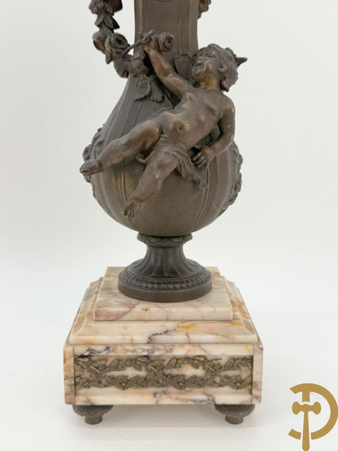Driedelige kunstbronzen garnituur bestaande uit klok met liggende dame met amfoor op marmeren basis, geflankeerd door paar cassolettes met cupido