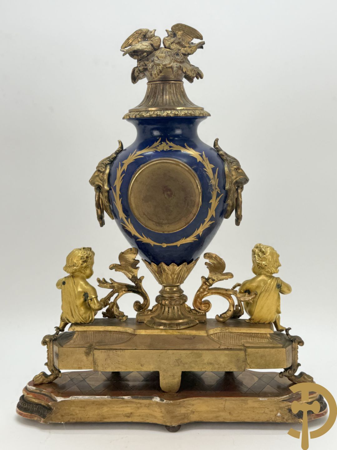 Driedelige vergulde bronzen garnituur bestaande uit pendule met blauw porseleinen coupe geflankeerd door 2 cupido