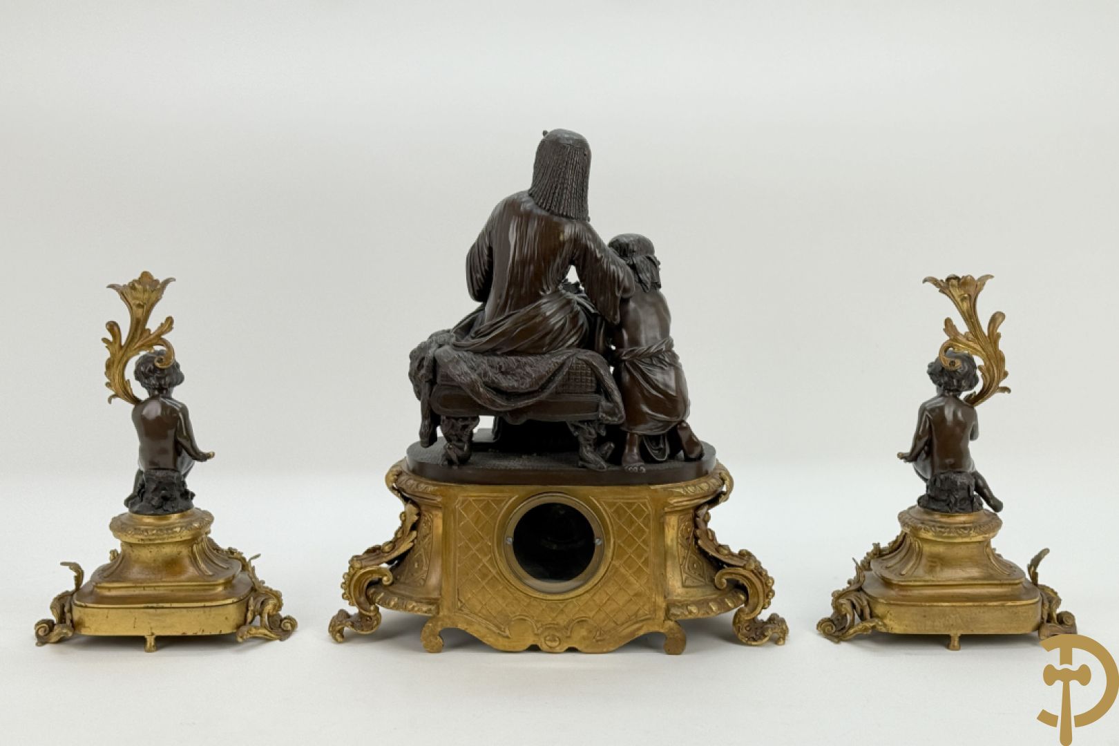 Driedelige bronzen garnituur bestaande uit middenstuk met bronzen vuurvergulde klok, Daubrée gemerkt à Nancy, bovenaan bekroond met Cleopatra met drinkbeker - getekend van Cumberworth sculpteur - geflankeerd door paar cupido