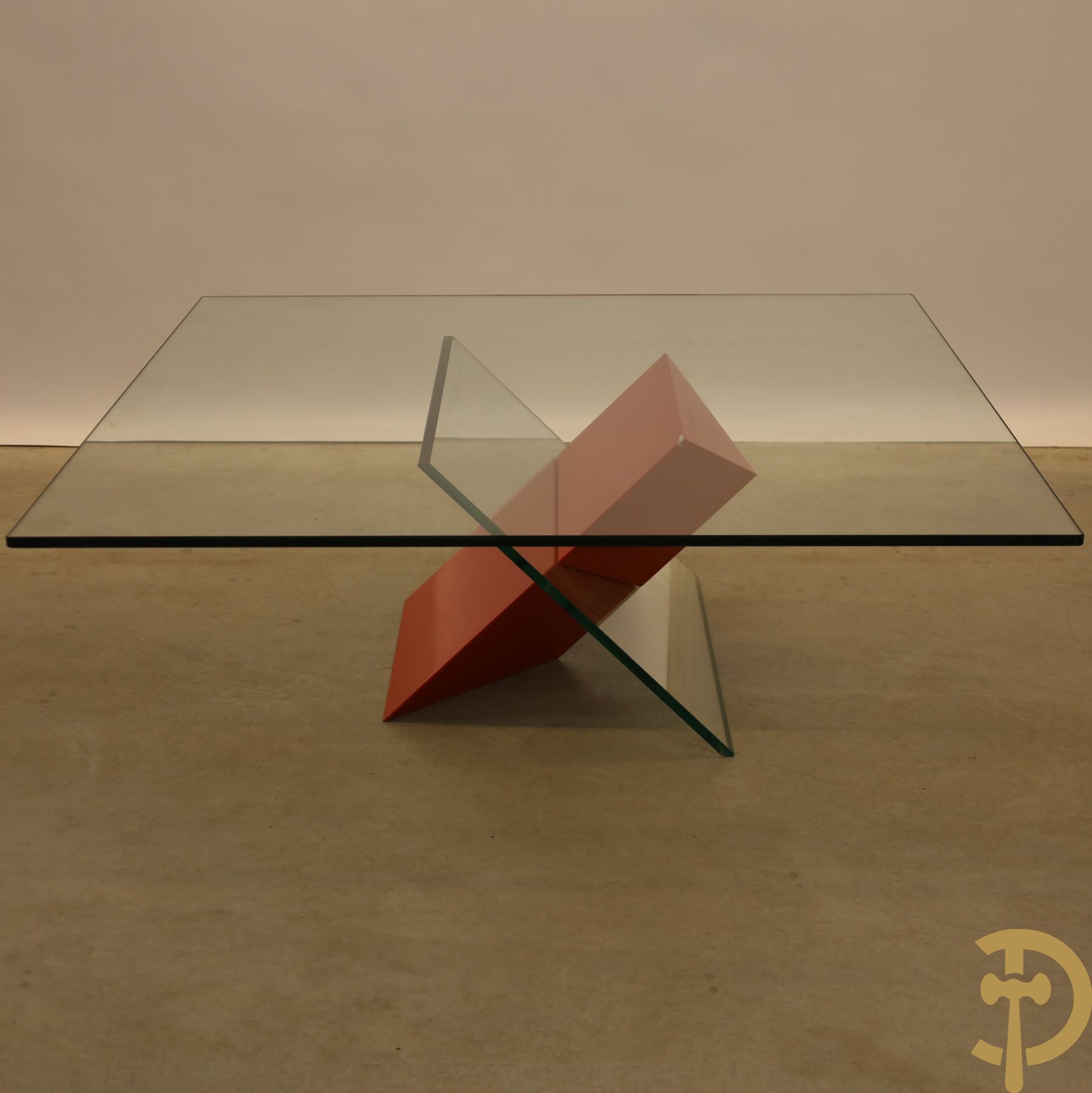 Design salontafel met glazen gepolijst blad op rood gelakte driehoekig prisma sokkel