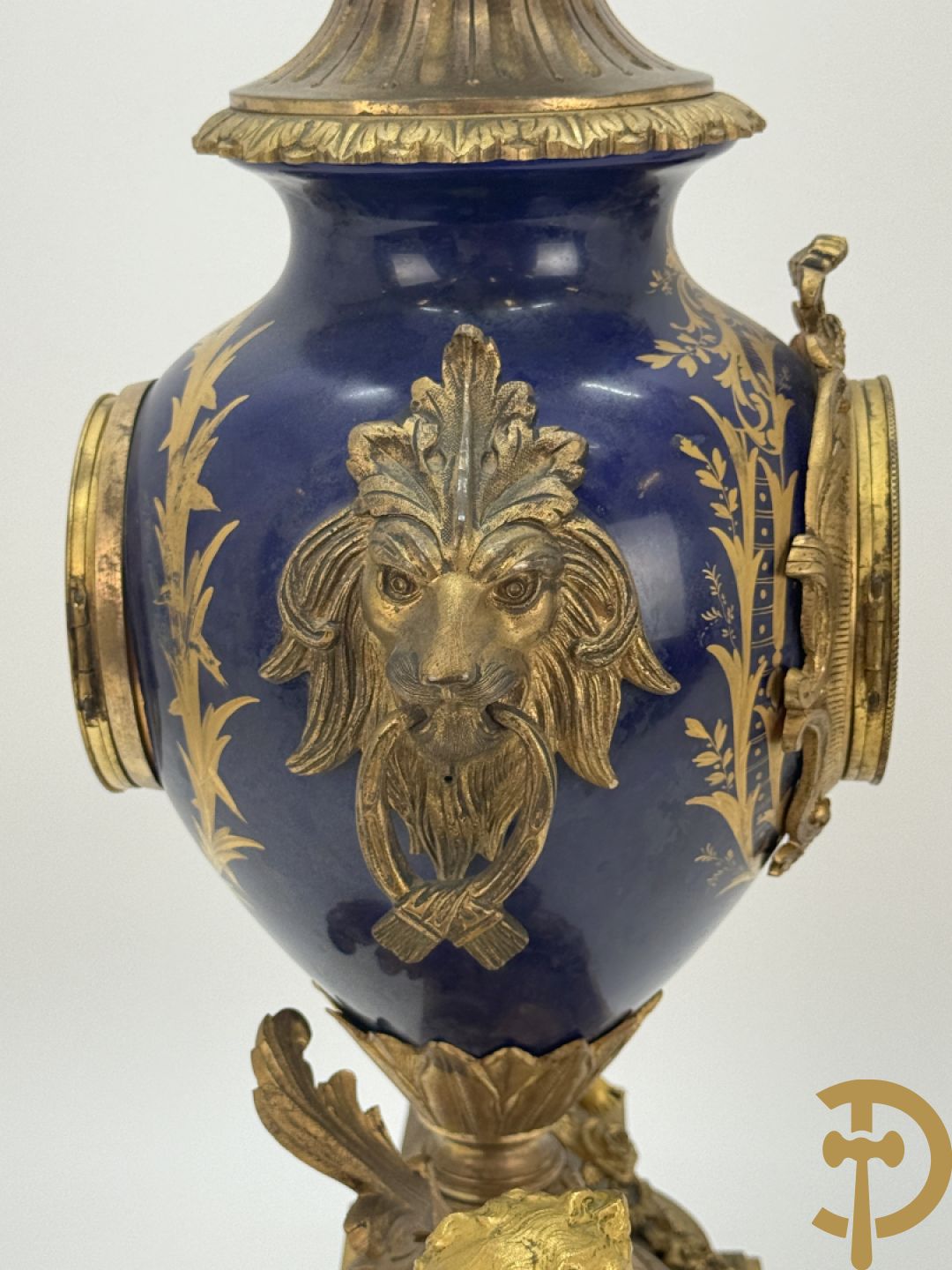 Driedelige vergulde bronzen garnituur bestaande uit pendule met blauw porseleinen coupe geflankeerd door 2 cupido