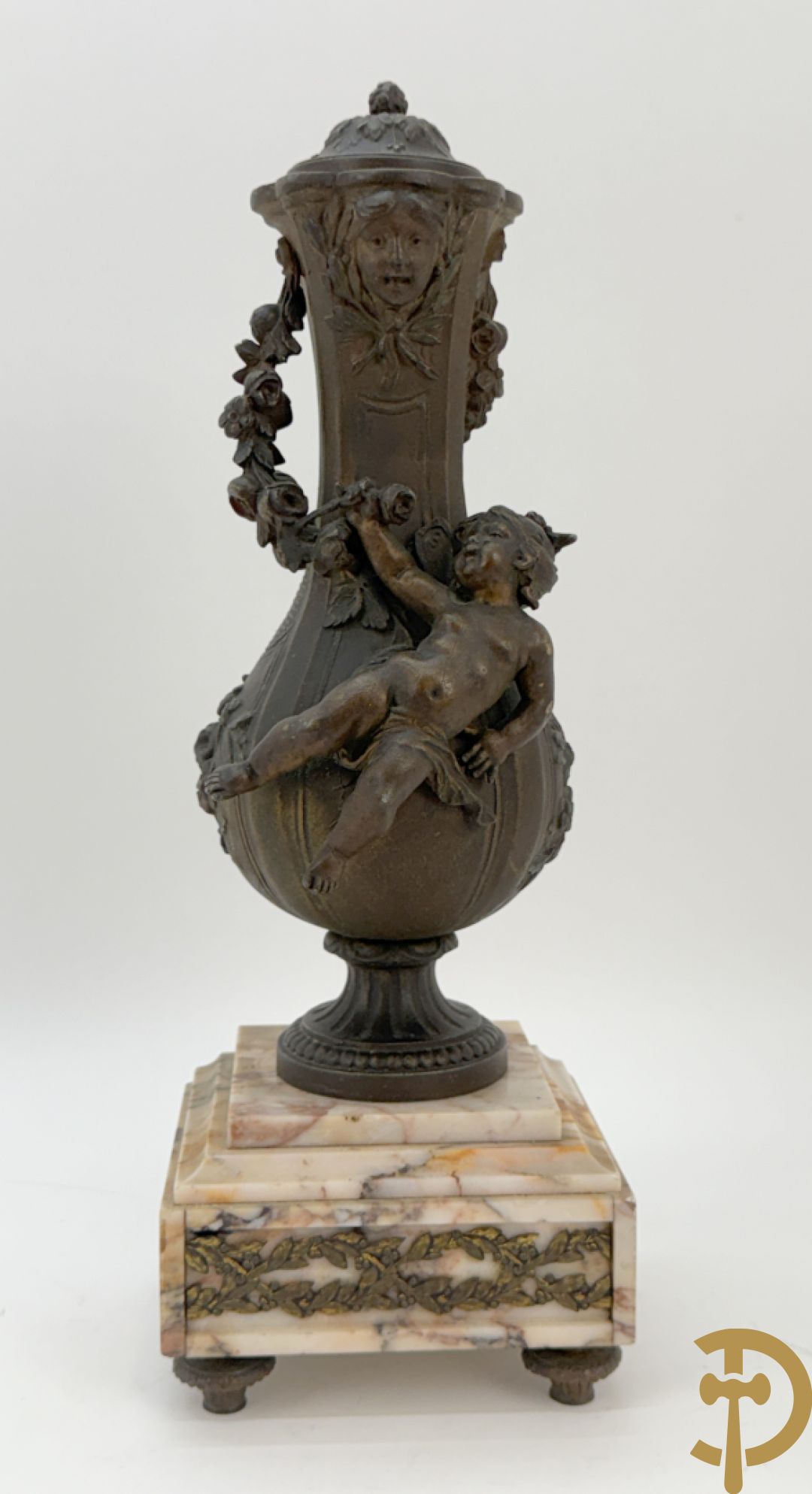 Driedelige kunstbronzen garnituur bestaande uit klok met liggende dame met amfoor op marmeren basis, geflankeerd door paar cassolettes met cupido
