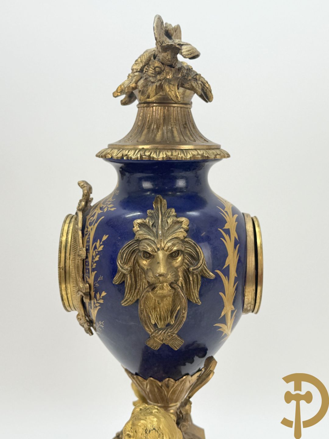 Driedelige vergulde bronzen garnituur bestaande uit pendule met blauw porseleinen coupe geflankeerd door 2 cupido