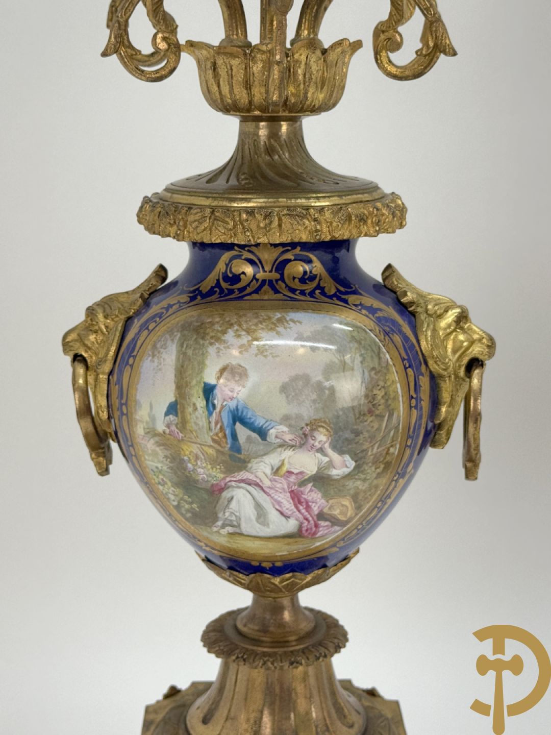 Driedelige vergulde bronzen garnituur bestaande uit pendule met blauw porseleinen coupe geflankeerd door 2 cupido