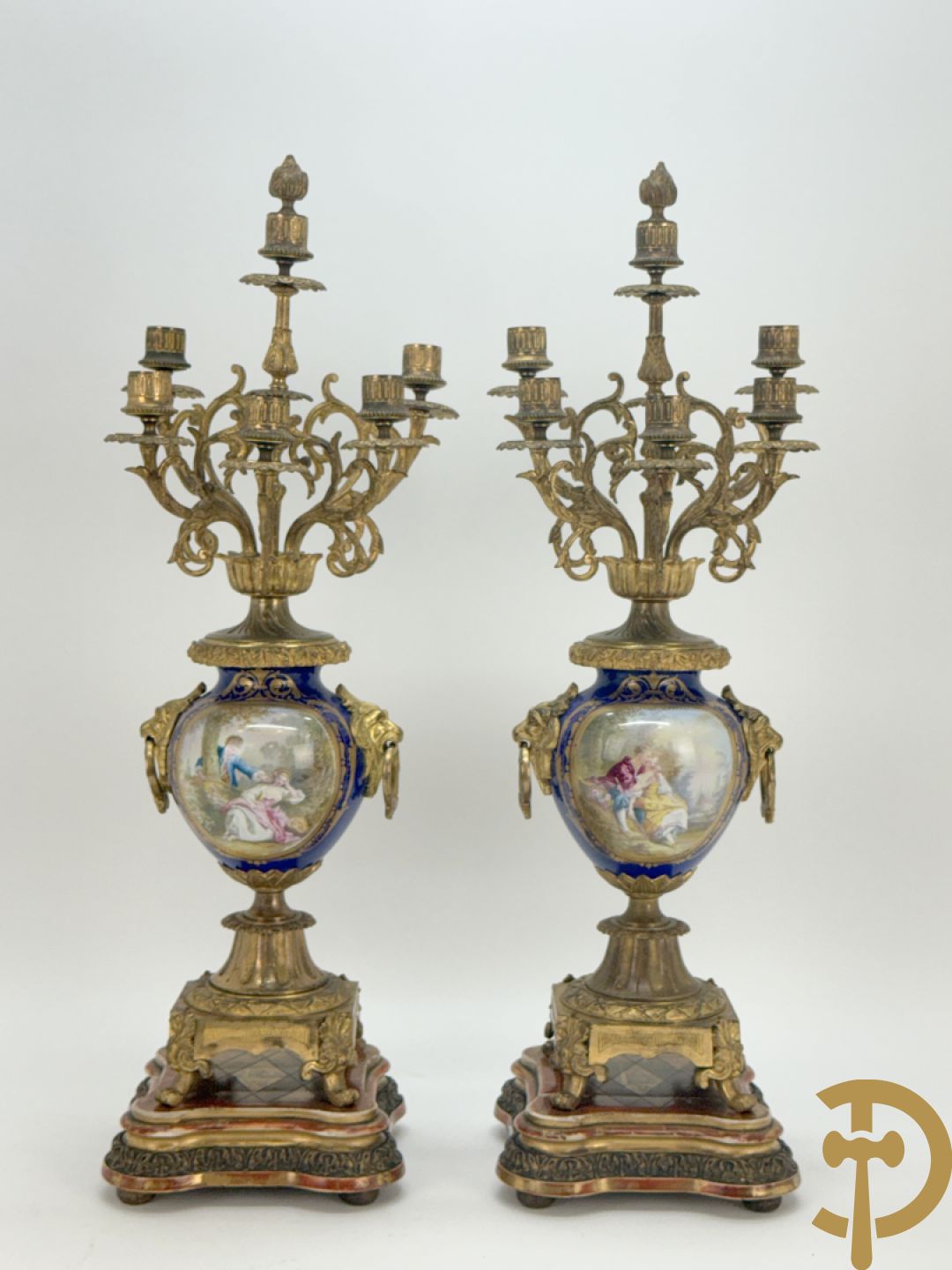 Driedelige vergulde bronzen garnituur bestaande uit pendule met blauw porseleinen coupe geflankeerd door 2 cupido