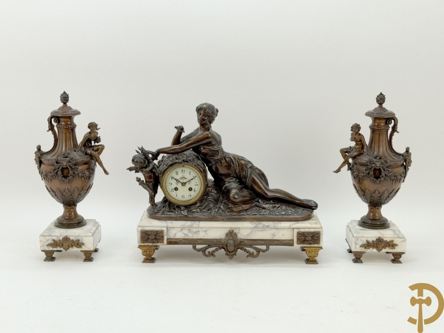 Driedelige schouwgarnituur met centrale pendule met liggende dame en cupido, geflankeerd door paar cassolettes met elegante dame