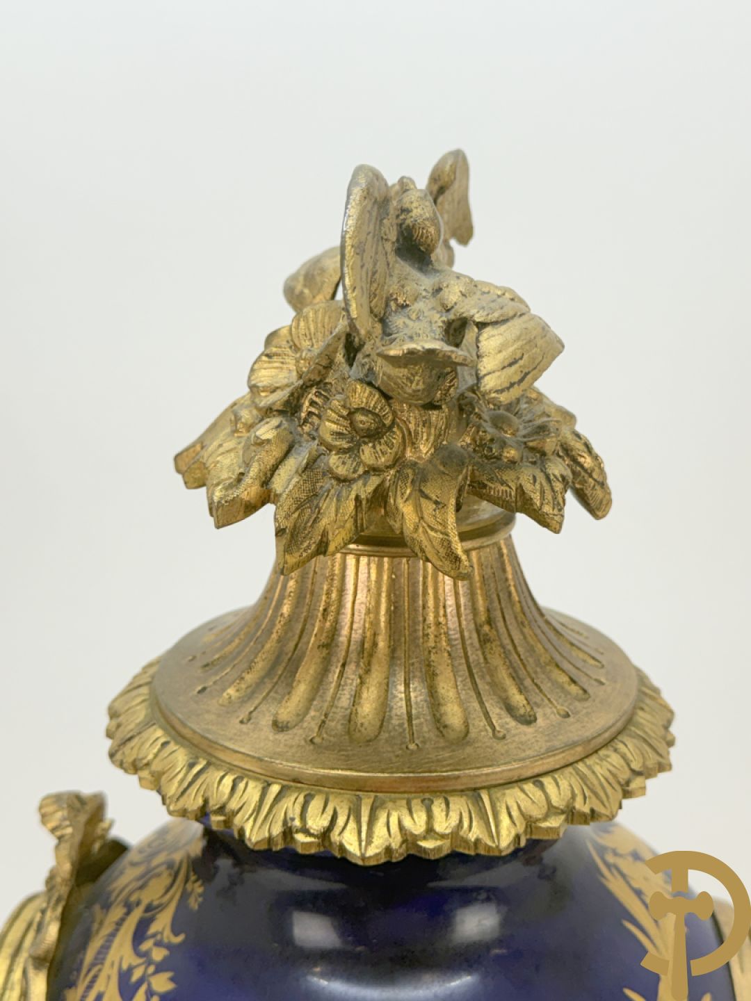 Driedelige vergulde bronzen garnituur bestaande uit pendule met blauw porseleinen coupe geflankeerd door 2 cupido