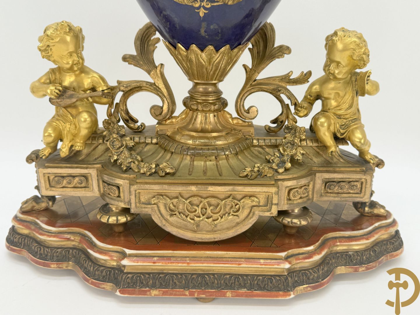Driedelige vergulde bronzen garnituur bestaande uit pendule met blauw porseleinen coupe geflankeerd door 2 cupido