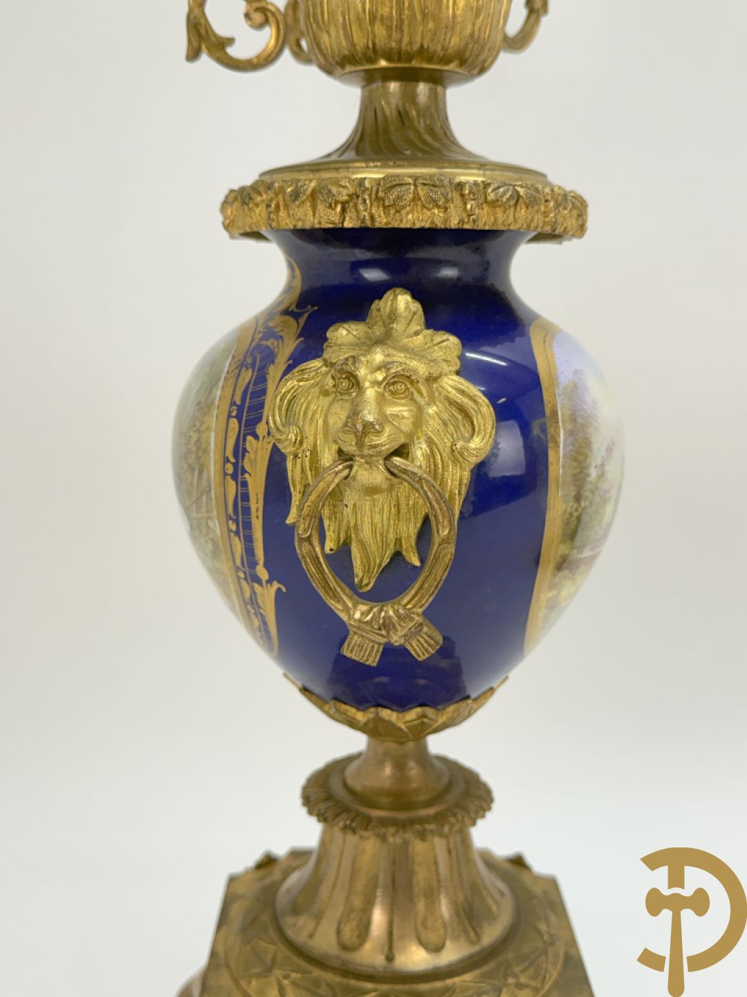 Driedelige vergulde bronzen garnituur bestaande uit pendule met blauw porseleinen coupe geflankeerd door 2 cupido