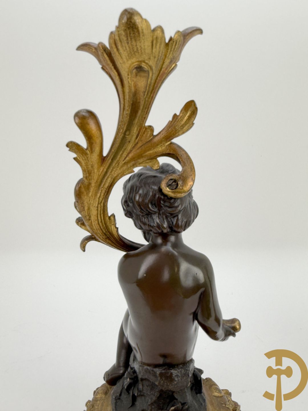 Driedelige bronzen garnituur bestaande uit middenstuk met bronzen vuurvergulde klok, Daubrée gemerkt à Nancy, bovenaan bekroond met Cleopatra met drinkbeker - getekend van Cumberworth sculpteur - geflankeerd door paar cupido