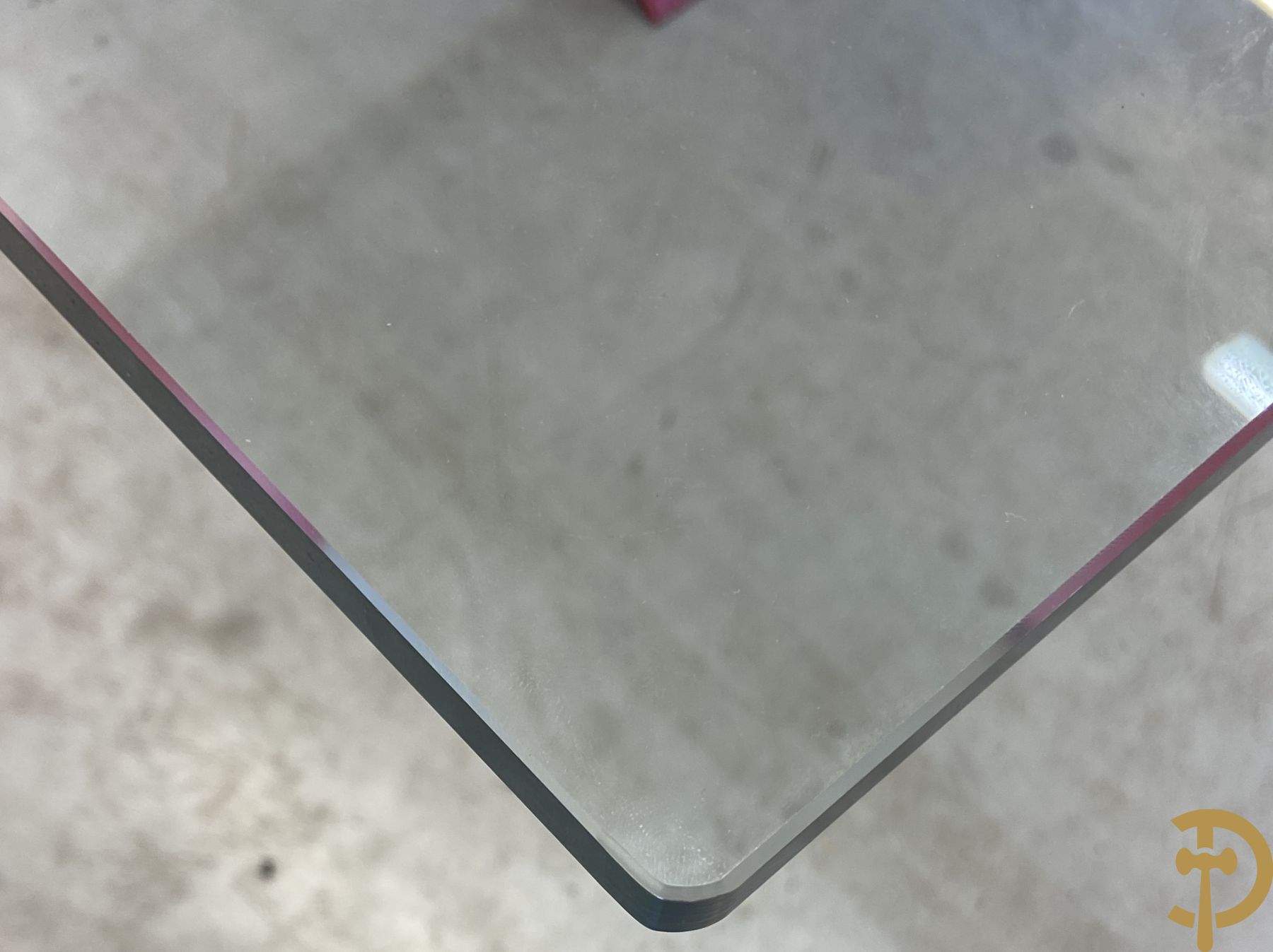 Design salontafel met glazen gepolijst blad op rood gelakte driehoekig prisma sokkel