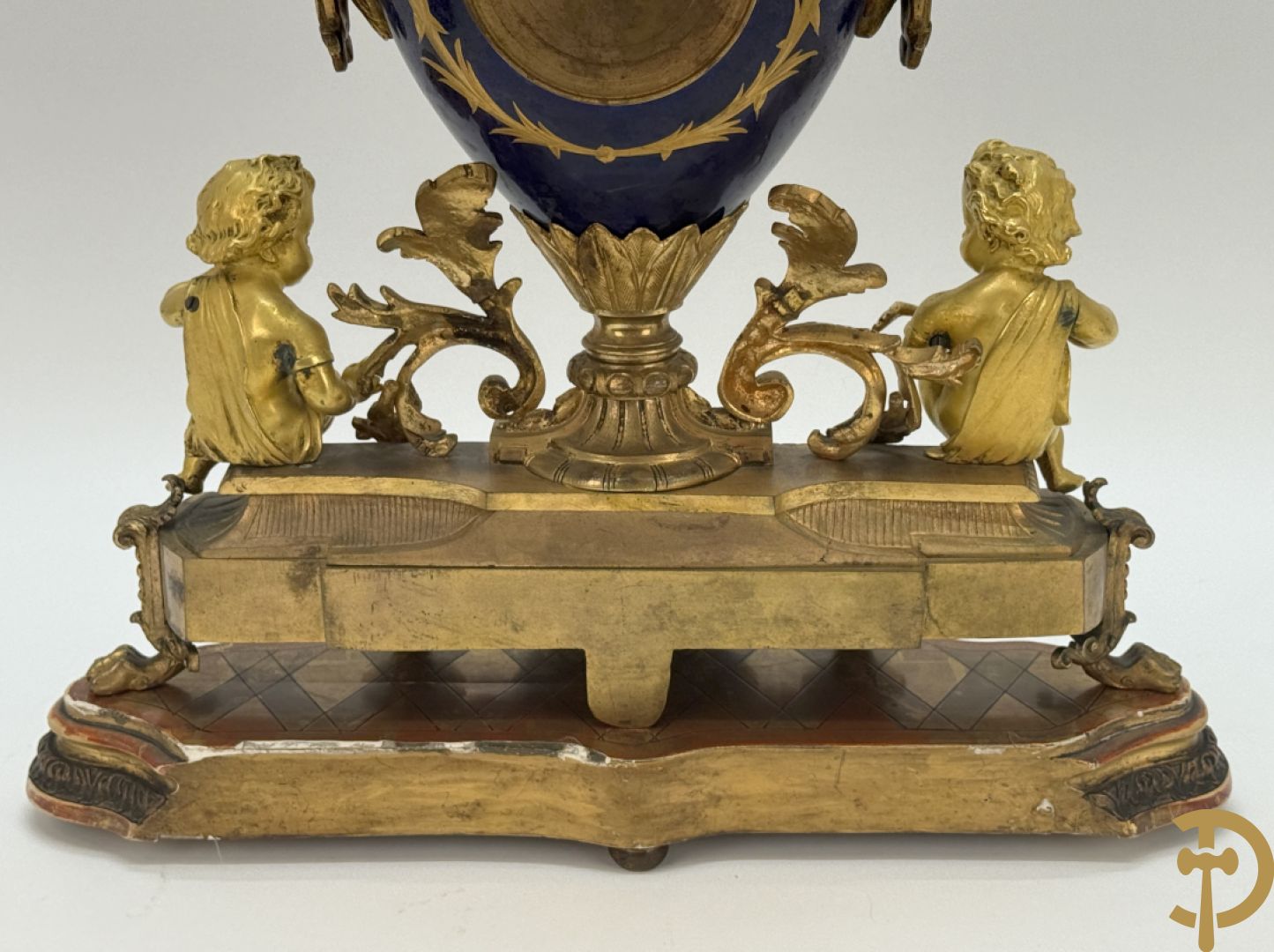 Driedelige vergulde bronzen garnituur bestaande uit pendule met blauw porseleinen coupe geflankeerd door 2 cupido