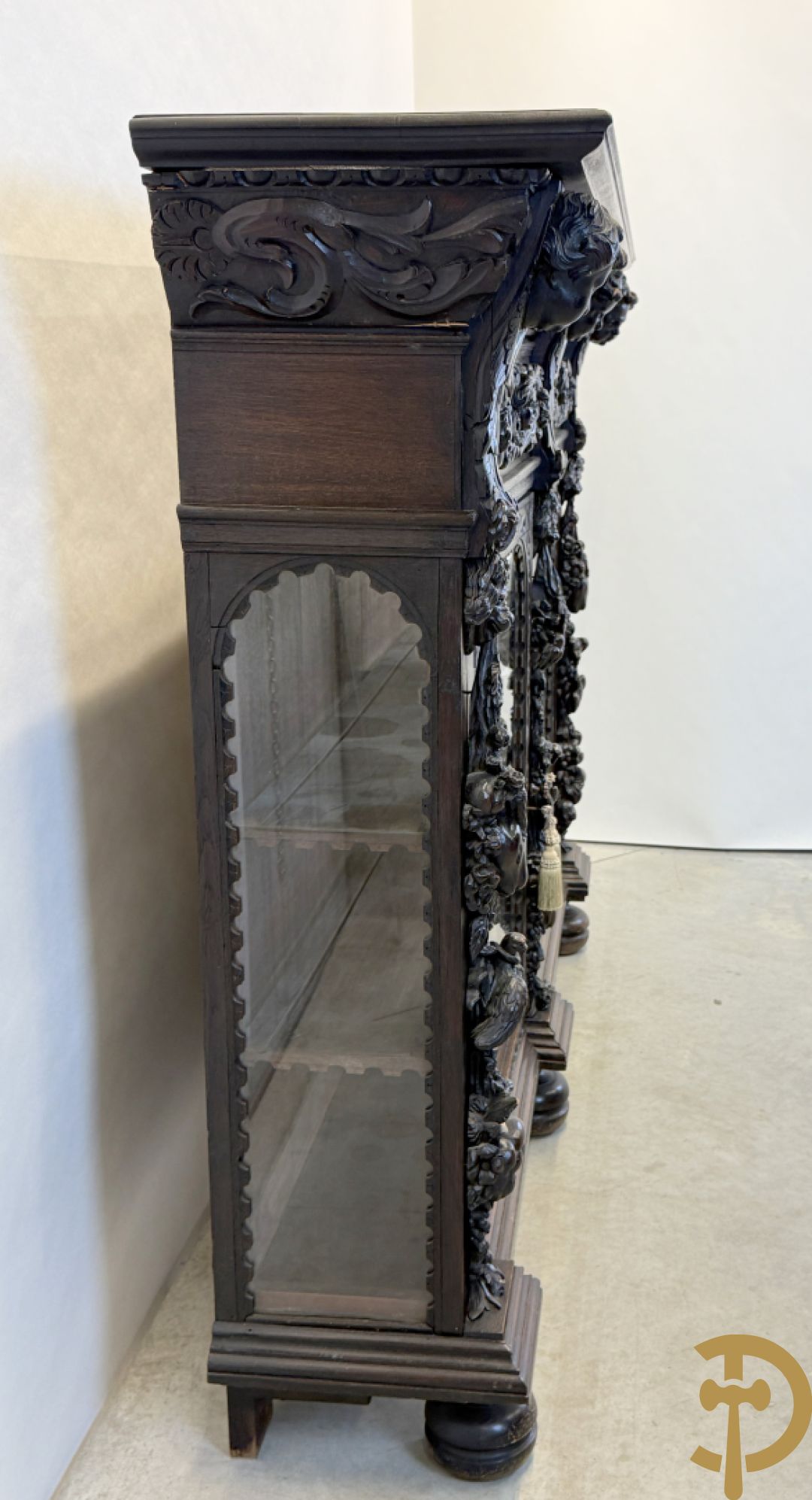 Tweedeursvitrine met Neo Renaissance sculptuur, bovenaan mlet cupidohoofden, bloemen en accanthusranken