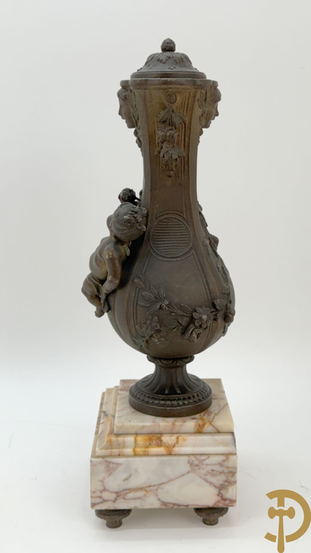 Driedelige kunstbronzen garnituur bestaande uit klok met liggende dame met amfoor op marmeren basis, geflankeerd door paar cassolettes met cupido