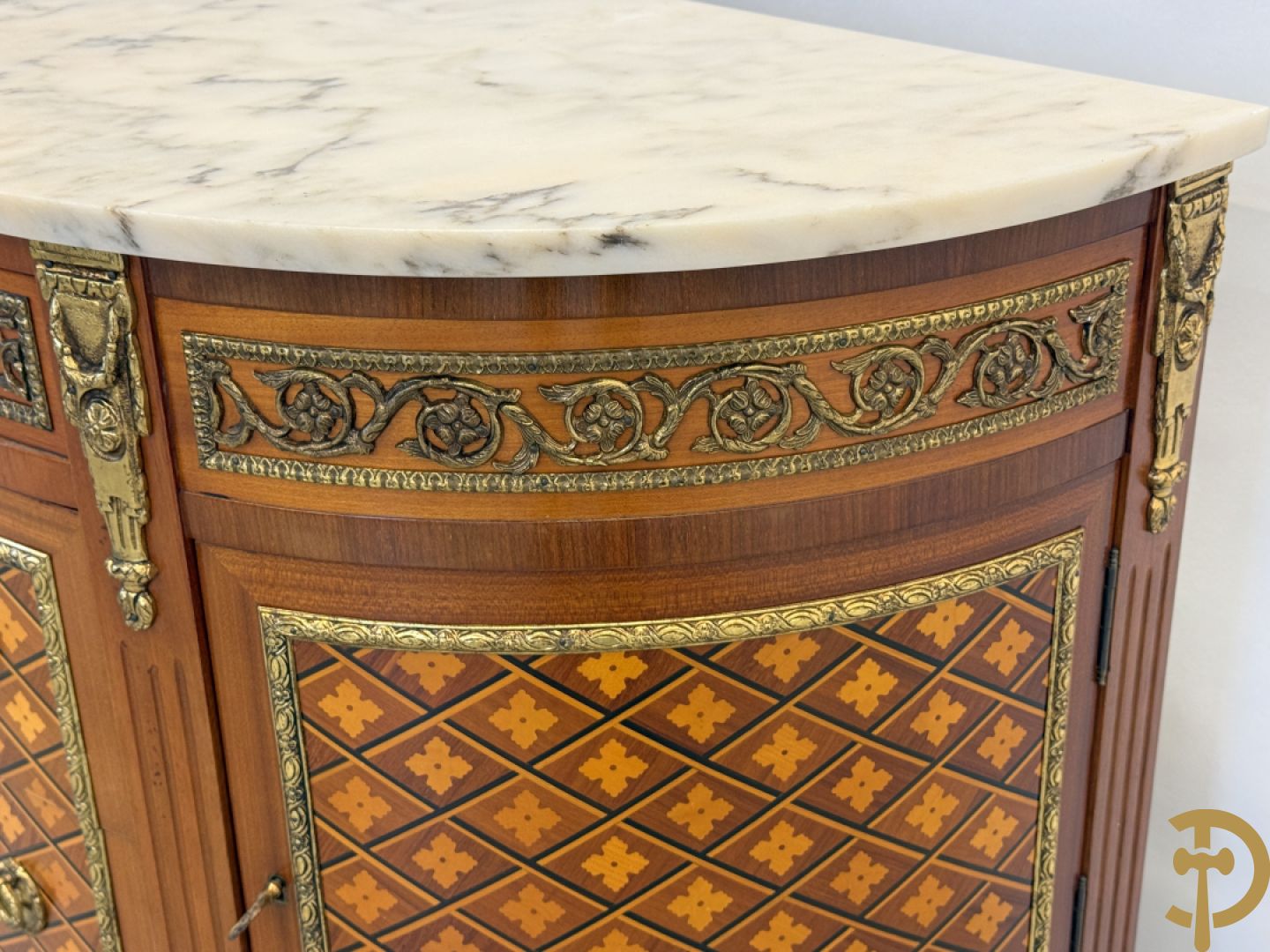 Halve maanvormige drieladencommode met 2 zijdelingse deuren, gemarketteerde bloemenmotieven en bronzen ornamenten, bovenaan bezet met marmeren blad
