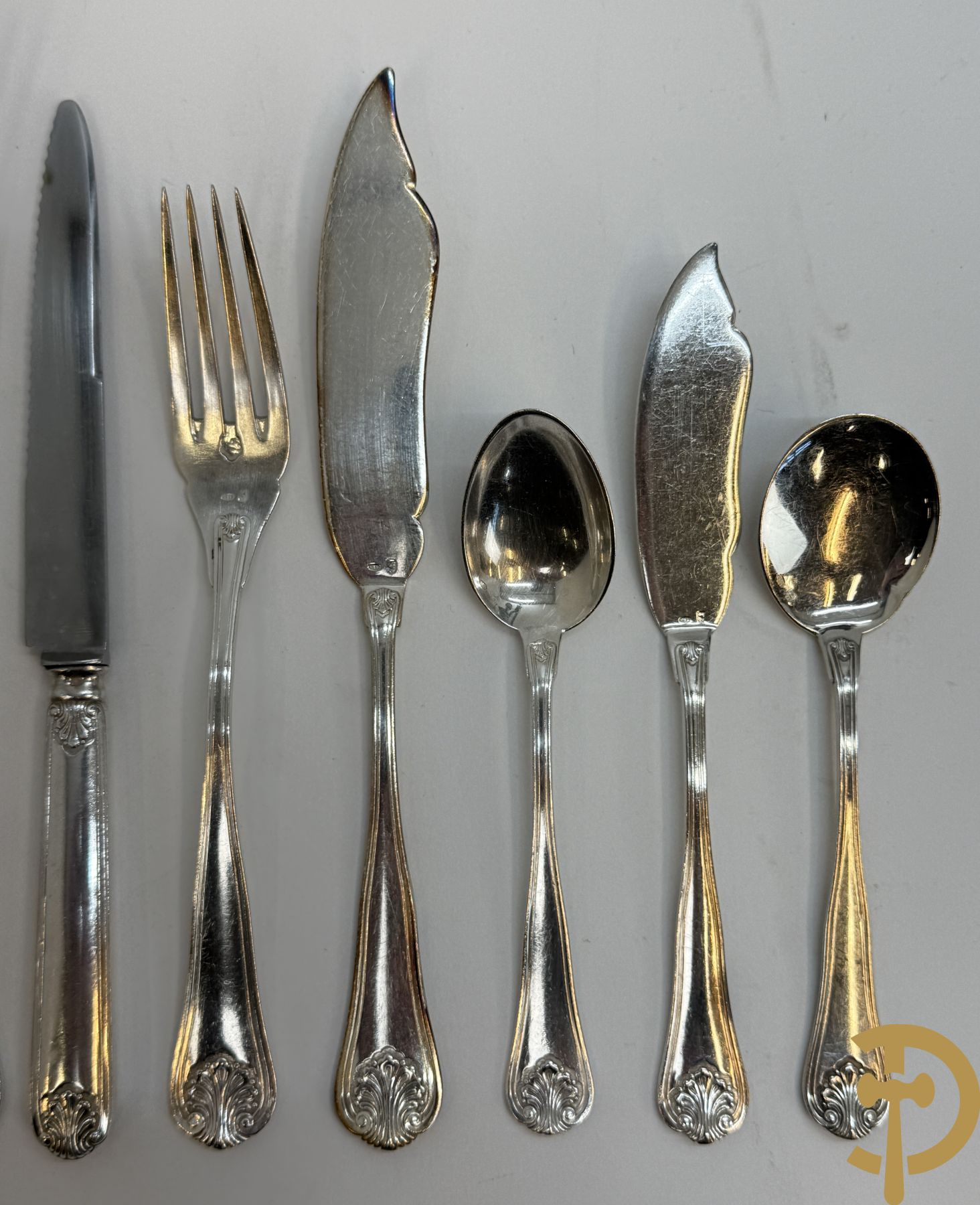 Massief zilveren bestek Wolfers bestaande uit 12 vorken (979 gram), 12 lepels (1028 gram), 11 messen, 12 visvorken (553 gram), 12 vismessen (690 gram), 12 dessertmessen, 10 koffielepels (296 gram), 12 ijslepels (369 gram), 3 botermesjes en scheplepeltje (165 gram), 5  grote stukken (samen 557 gram) waarvan slacouvert, 2 taartscheppen en wildvork + sauslepel met zelfde decor maar Metal Blanc