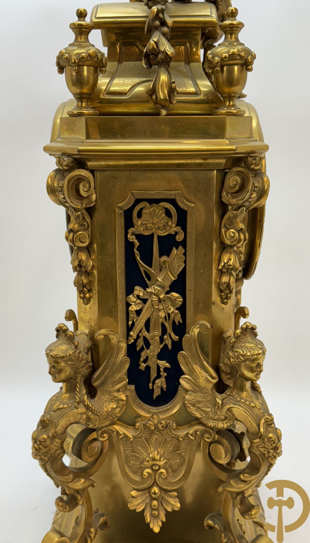 Bronzen pendule met kariathyden bezet en bovenaan met gevleugeld dameshoofd