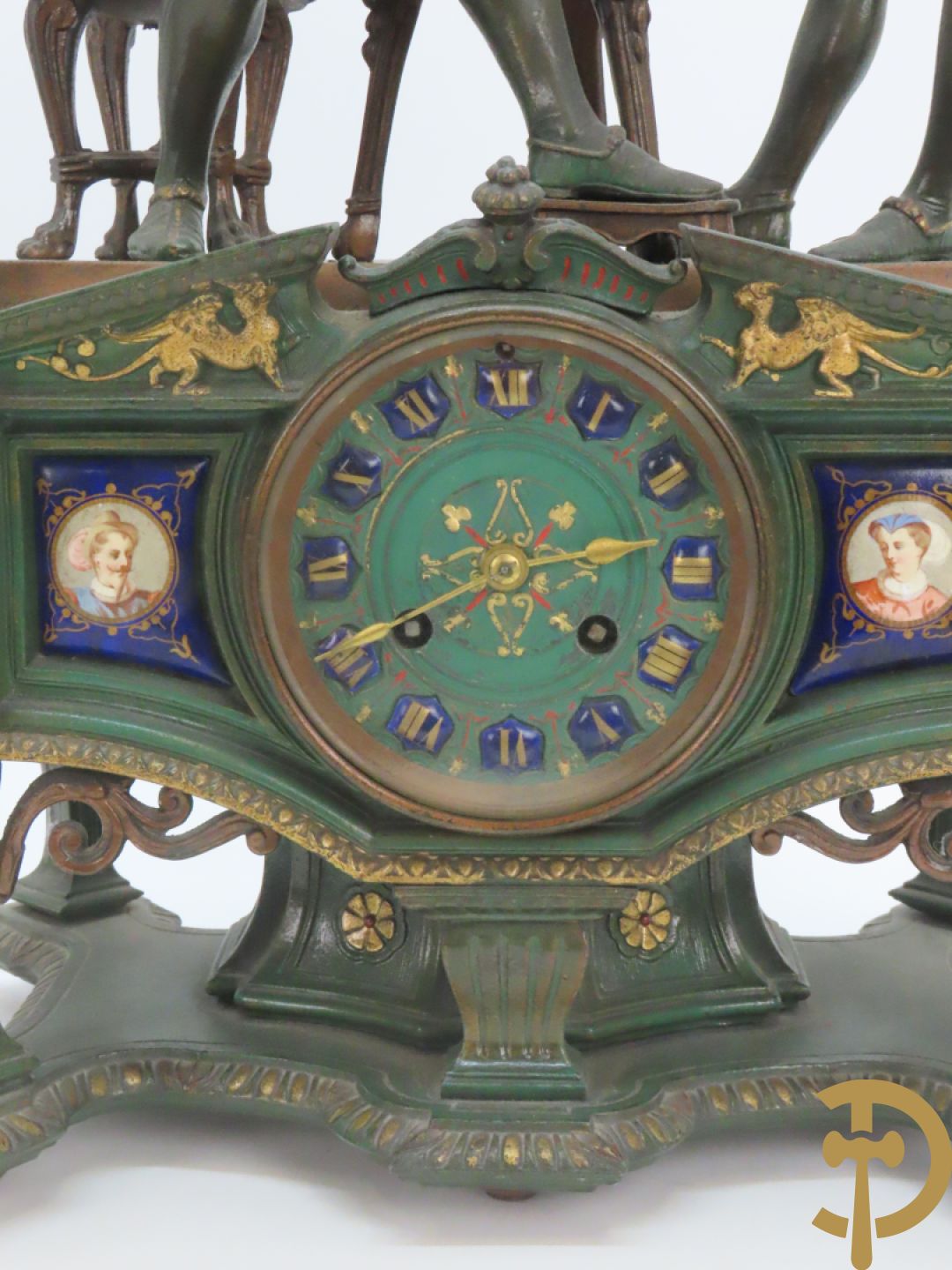 Driedelige kunstbronzen garnituur bestaande uit pendule met paar schakende edelheren, bezet met kariatiden - geflankeerd door paar driearmige kandelaars gehouden door 2 edelheren