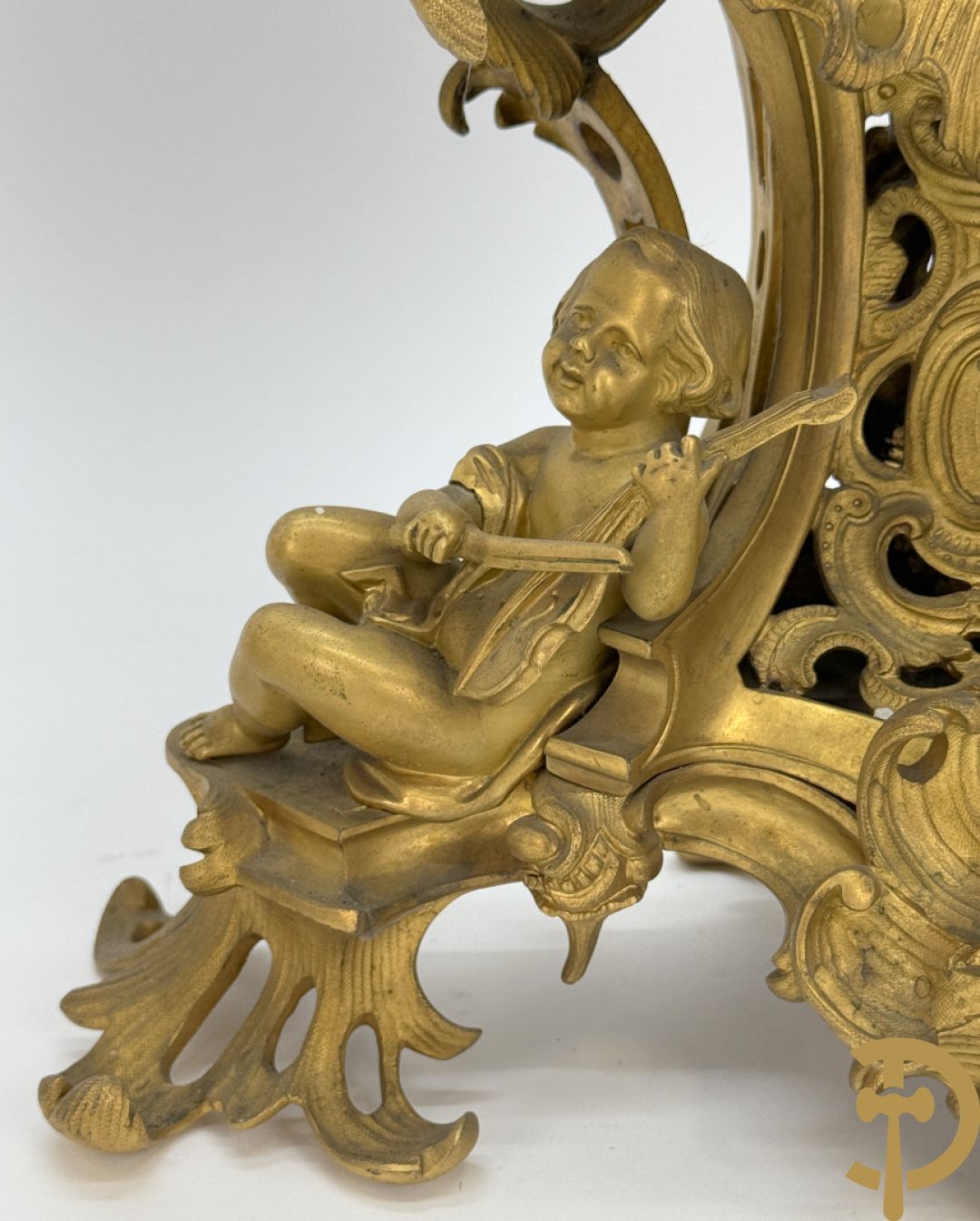 Driedelige vuurvergulde bronzen garnituur, Louis XV stijl, bestaande uit middenstuk met klok omgeven door musicerende cupido