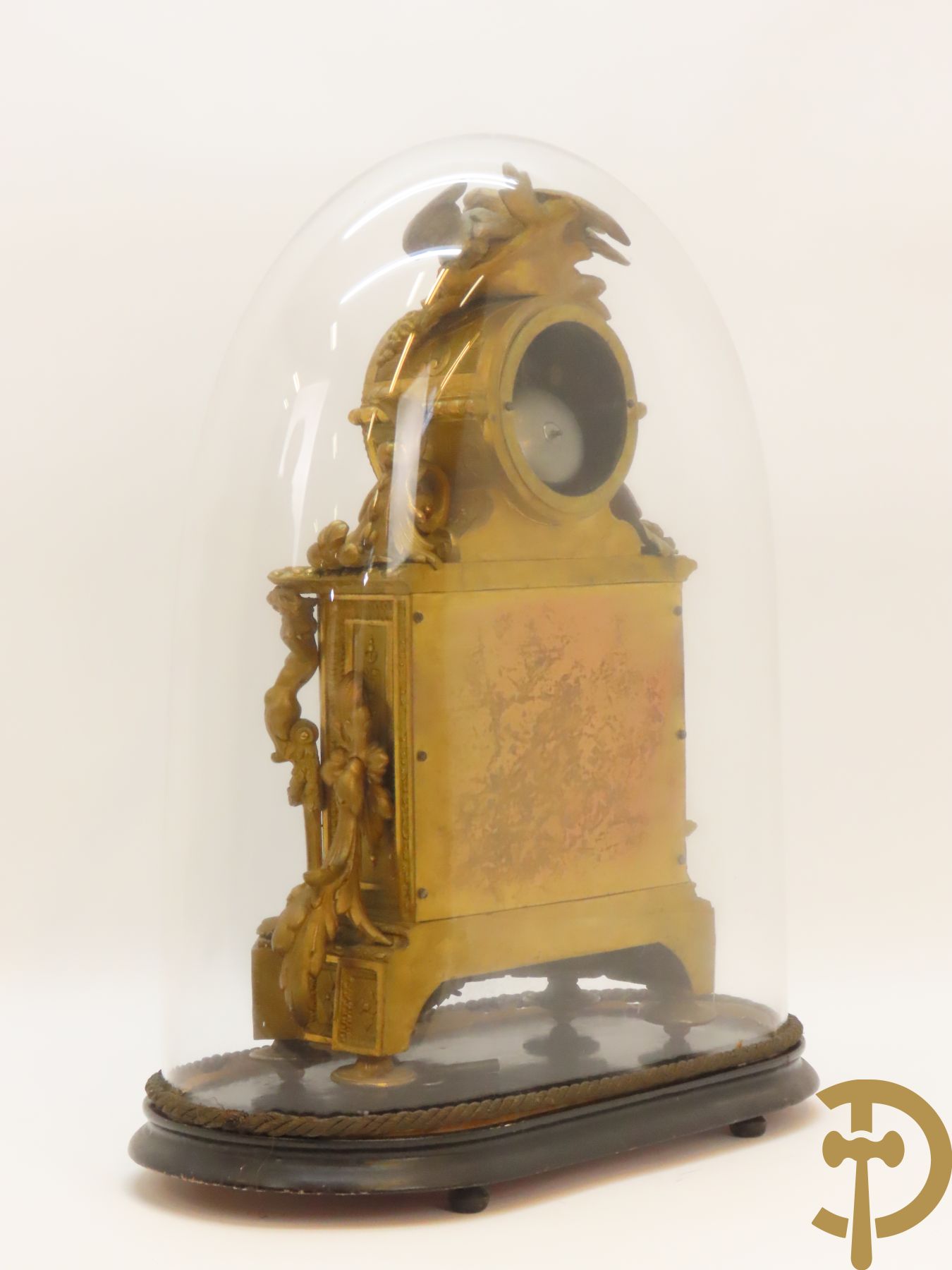 Vergulde pendule in zamak, wijzerplaat bezet met porseleinen plakkettes - bovenaan met vogelpaar, zijdelings met kariathyden houdende een bloementroffee - onder glazen stolp