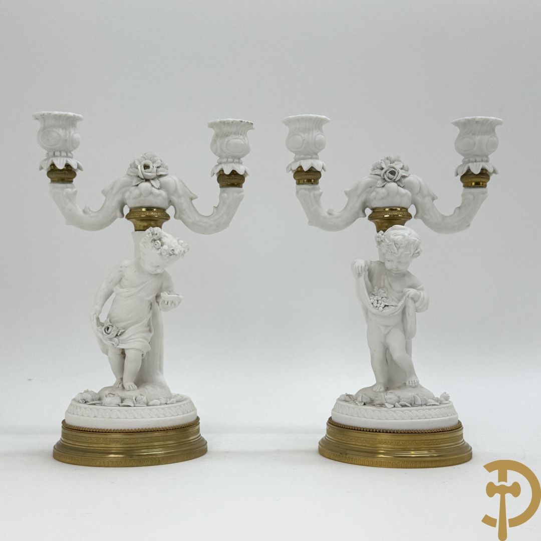 Paar biscuit kandelaars met cupido's, fruit en bloemen