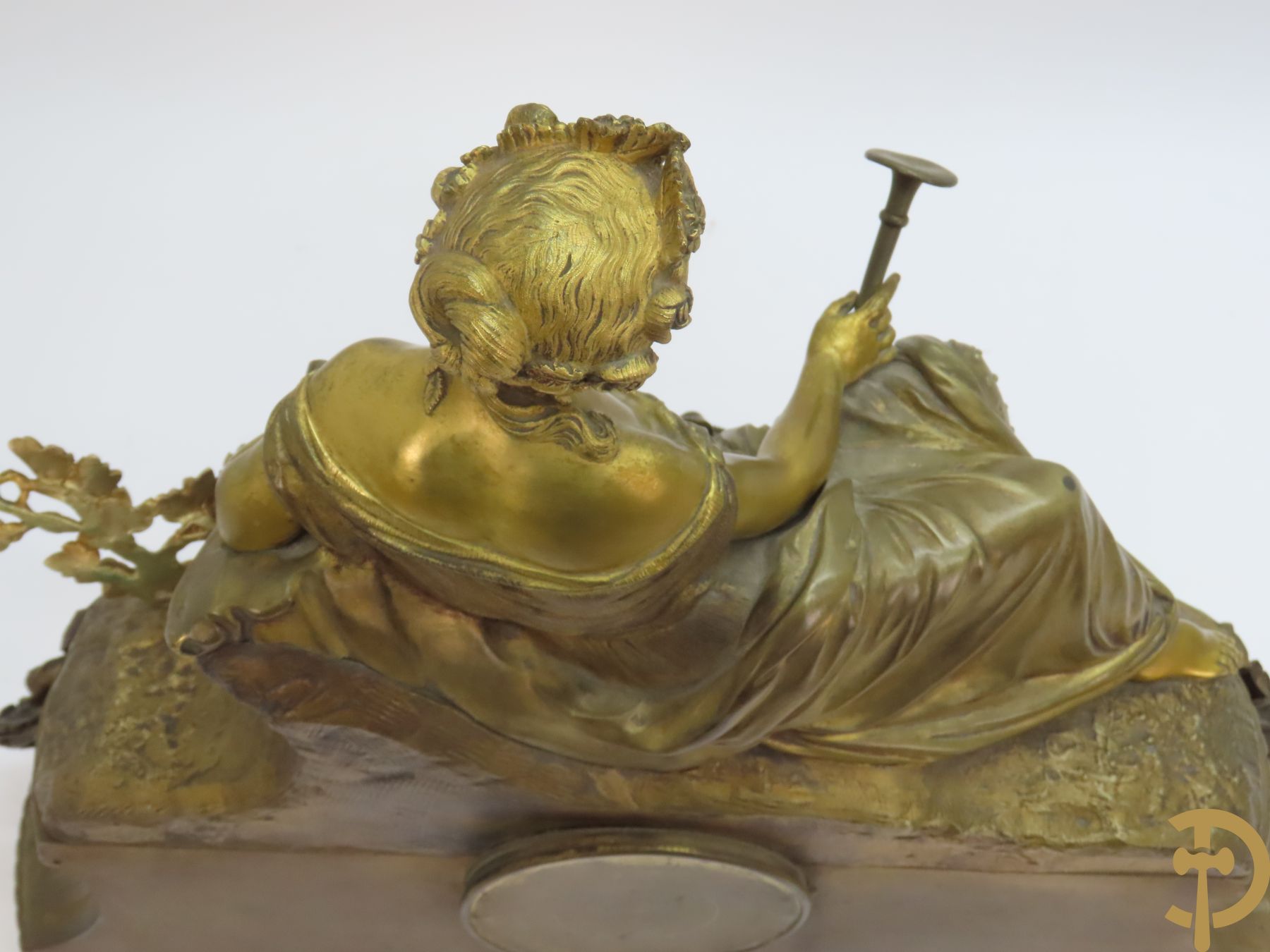 Bronzen schouwstuk met zittende dame met trompet en harp op horloge met muziekinstrumenten