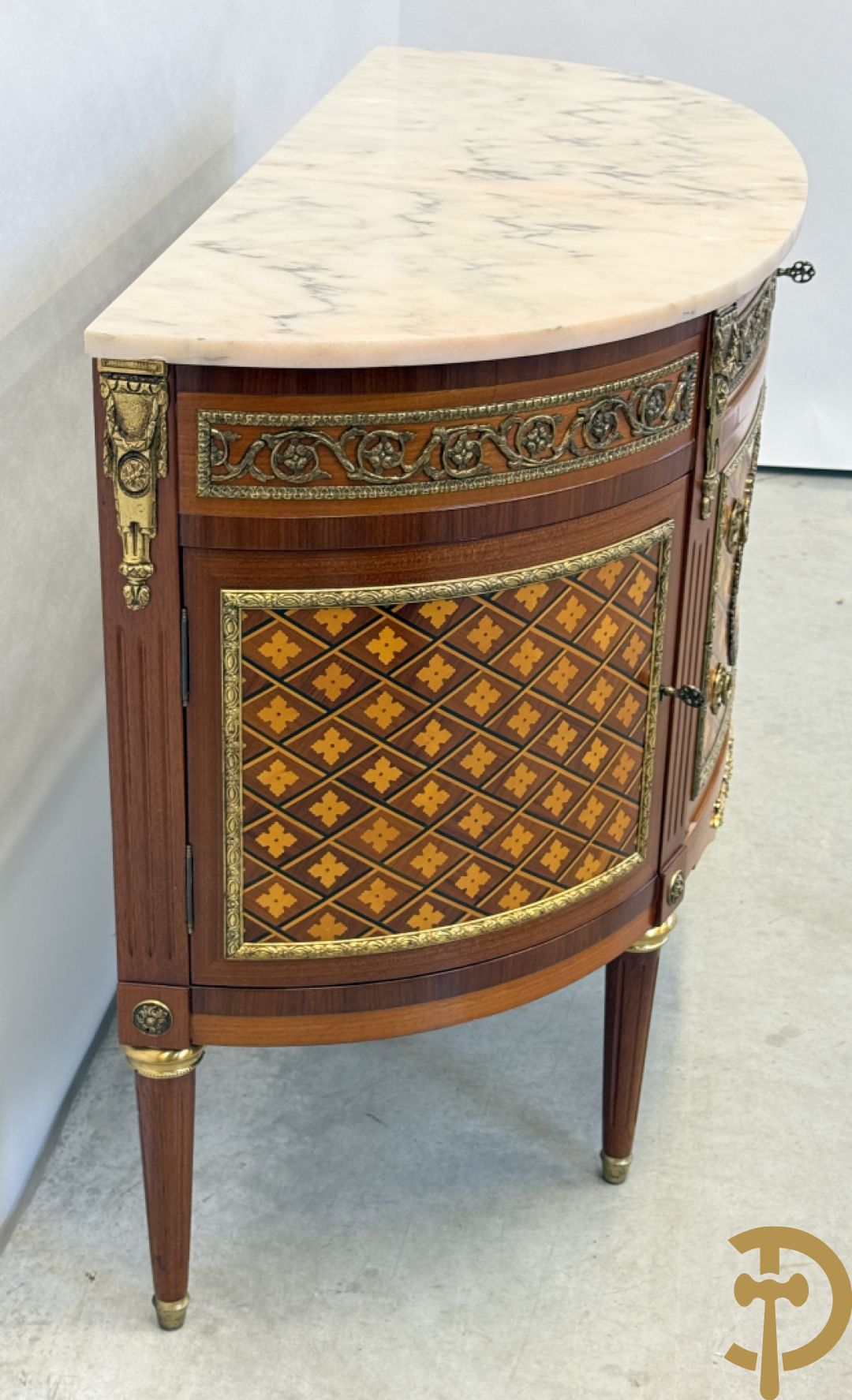 Halve maanvormige drieladencommode met 2 zijdelingse deuren, gemarketteerde bloemenmotieven en bronzen ornamenten, bovenaan bezet met marmeren blad