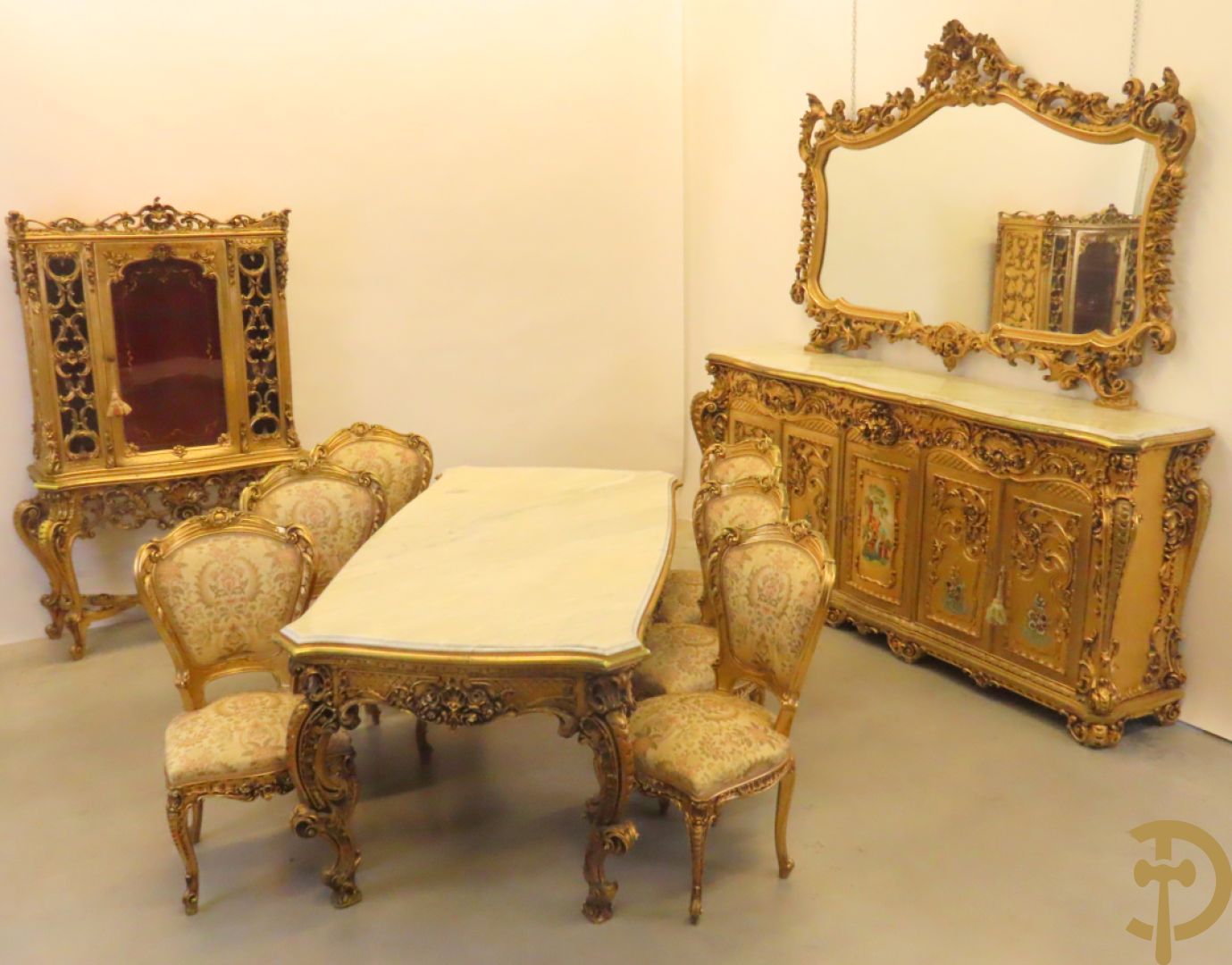 Uitzonderlijke vergulde Louis XV eetkamer bestaande uit vijfdeursdressoir met voluutvormige accanthusranken en rocailles, beschilderd met bloemenmotieven en centraal tafererel met hoornen des overvloeds + bijhorende spiegel vergulde tafel op voluutvormige poten met zes bijhorende stoelen + vitrine met accanthusranken en centrale deur, op voluutvormige poten