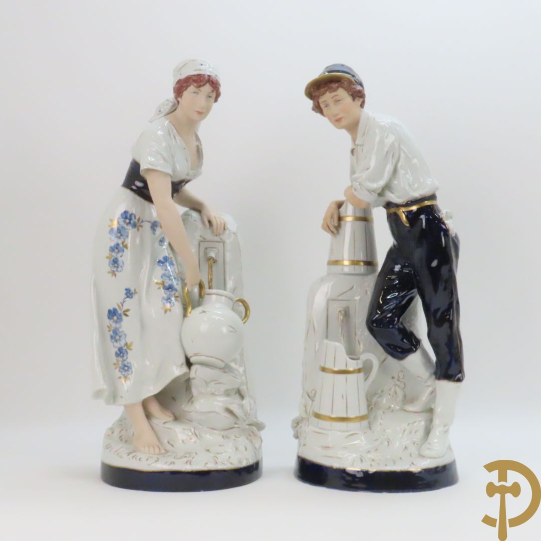 Paar Royal Dux personages van dame en heer bij de waterkraan, onderaan gemerkt en genummerd 10965 en 10563