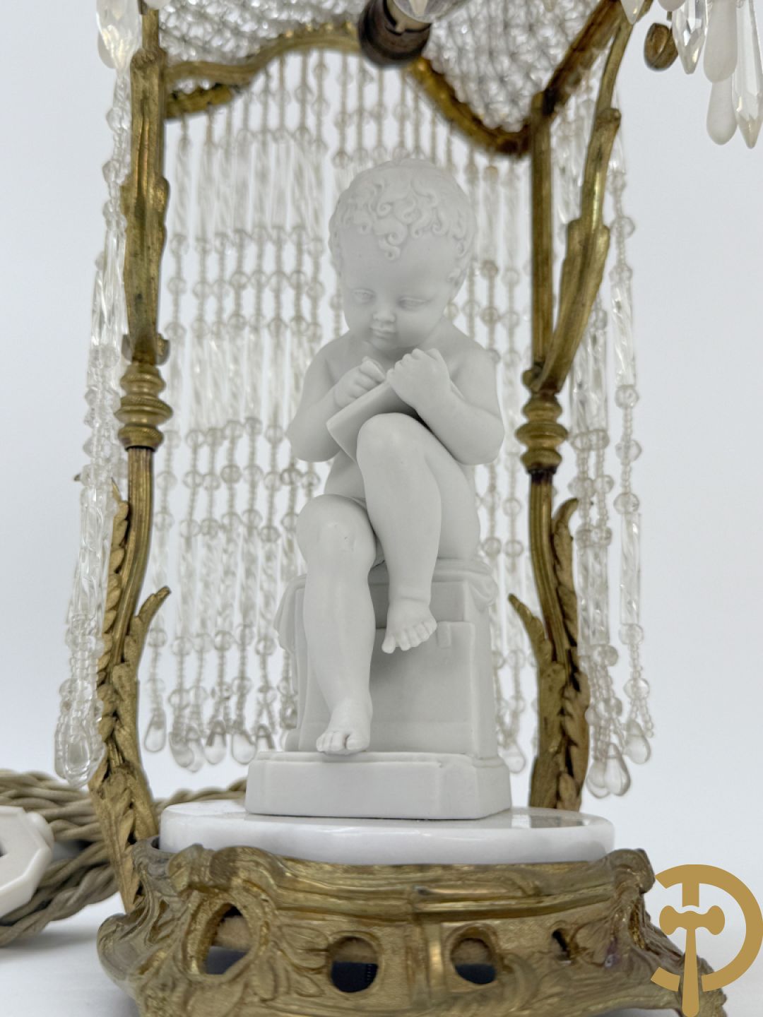 Biscuitbeeld van schrijvende cupido onder bronzen dakje met kristallen bellen bezet - op marmeren sokkel gemonteerd